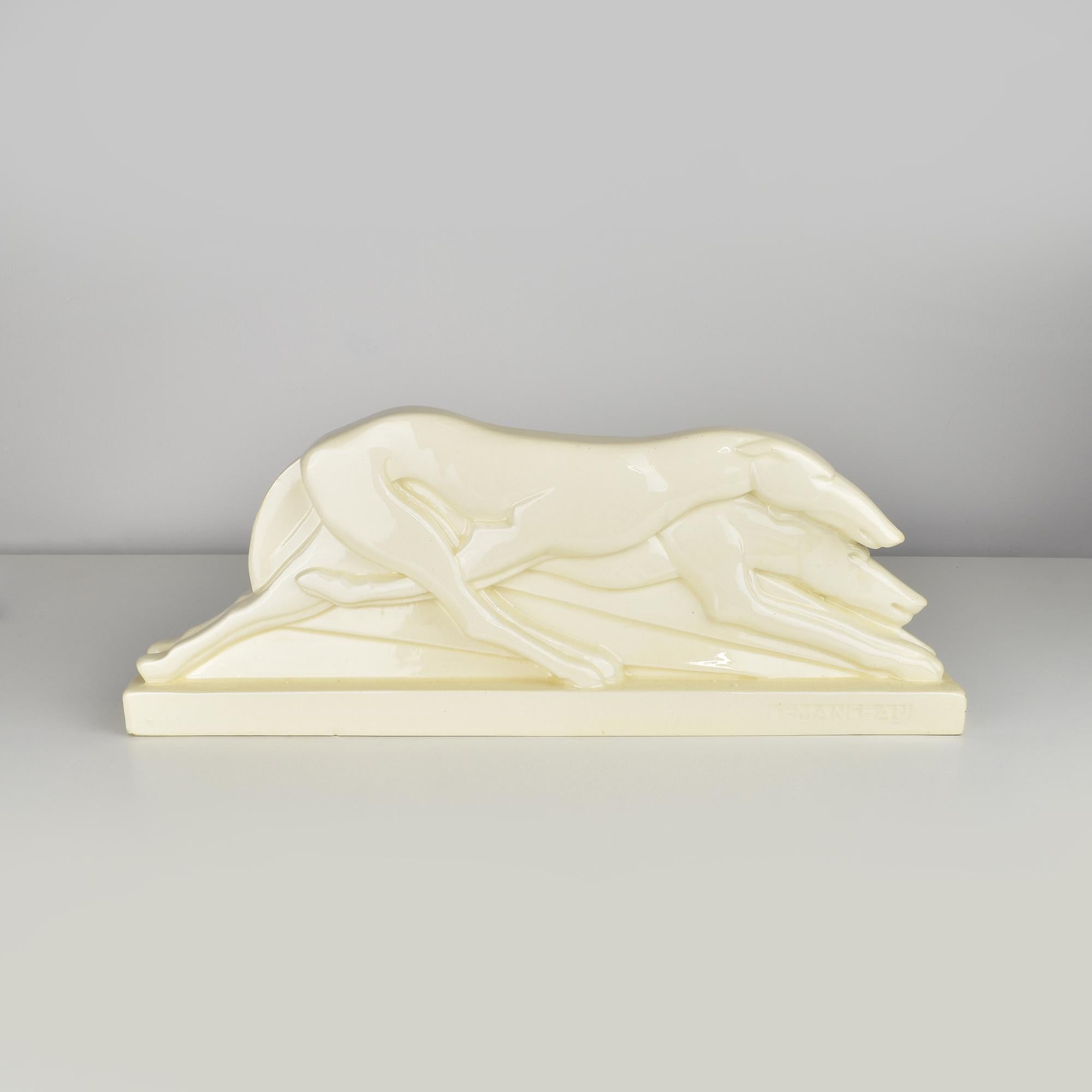A rare majolica ceramic sculpture by Charles Lemanceau for Saint Clément. The piece depicts two sleek, streamlined greyhounds in motion, capturing the essence of speed and grace. The design is distinctly Art Deco, with its stylized, geometric form