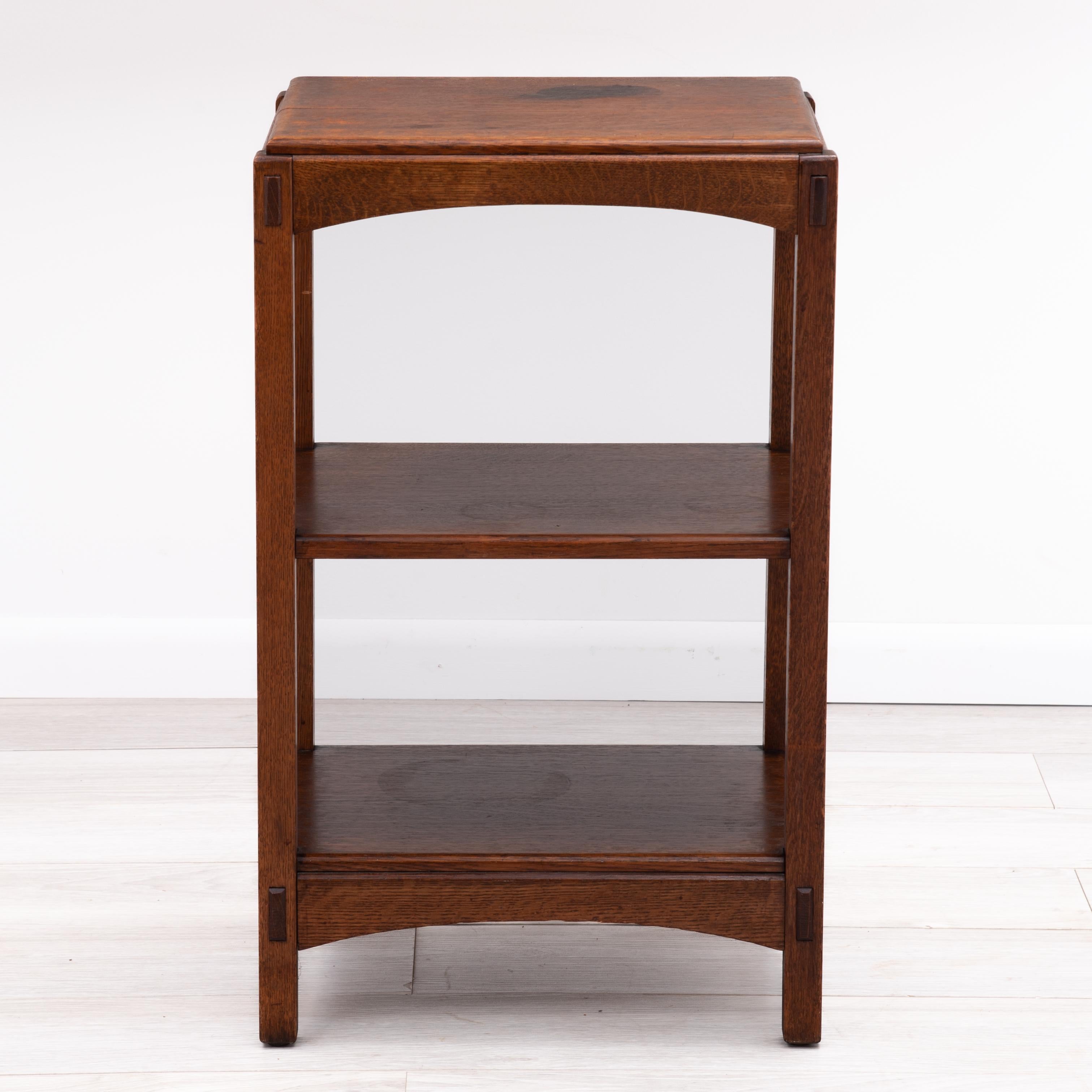A Charles Limbert Arts & Crafts magazine stand with two shelves, arched aprons, pinned through-tenons and inset top. Fully marked with the branded mark under the bottom shelf.