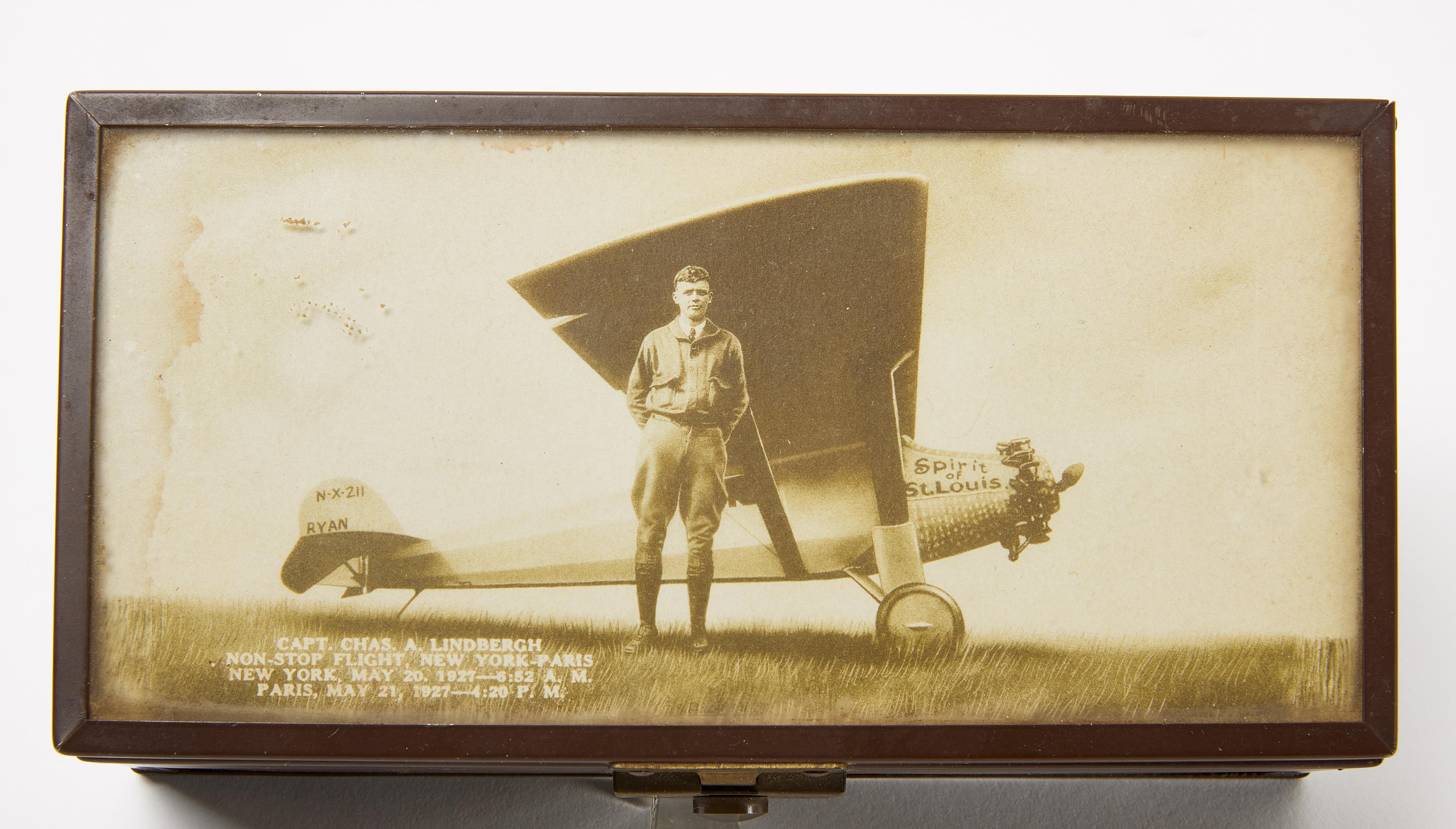 Charles Lindbergh humidor or cigar box. Wood lined. Coated metal with period photo insert captioned: 'Capt. Chas. A. Lindbergh, non-stop flight, New York–Paris. New York, May 20, 1927—6:52 A.M. Paris, May 21, 1927—4:20 P.M.' American, circa 1927. 