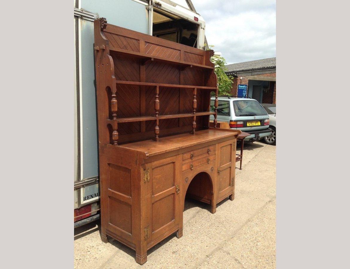 An Arts & Crafts oak dresser designed by Charles Locke Eastlake with good provenance.
The dresser top with chevron back boards and four open shelves with turned supports and through pegged joints to the top shelf and carved plumes to each upper