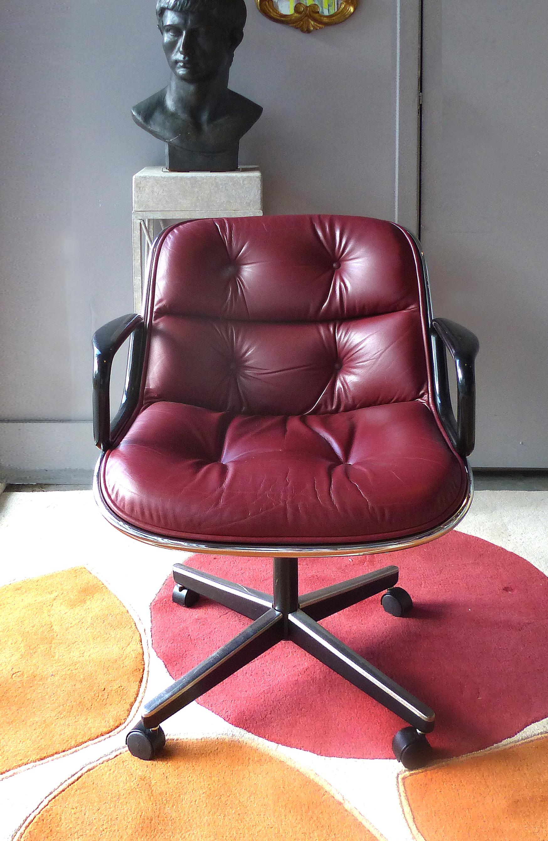 Offered for sale is a pair of iconic Mid-Century Modern executive swivel chairs by Charles Pollock for Knoll International. The chairs are luxuriously upholstered in a rare maroon leather accented in black and chrome. The chairs swivel upon a