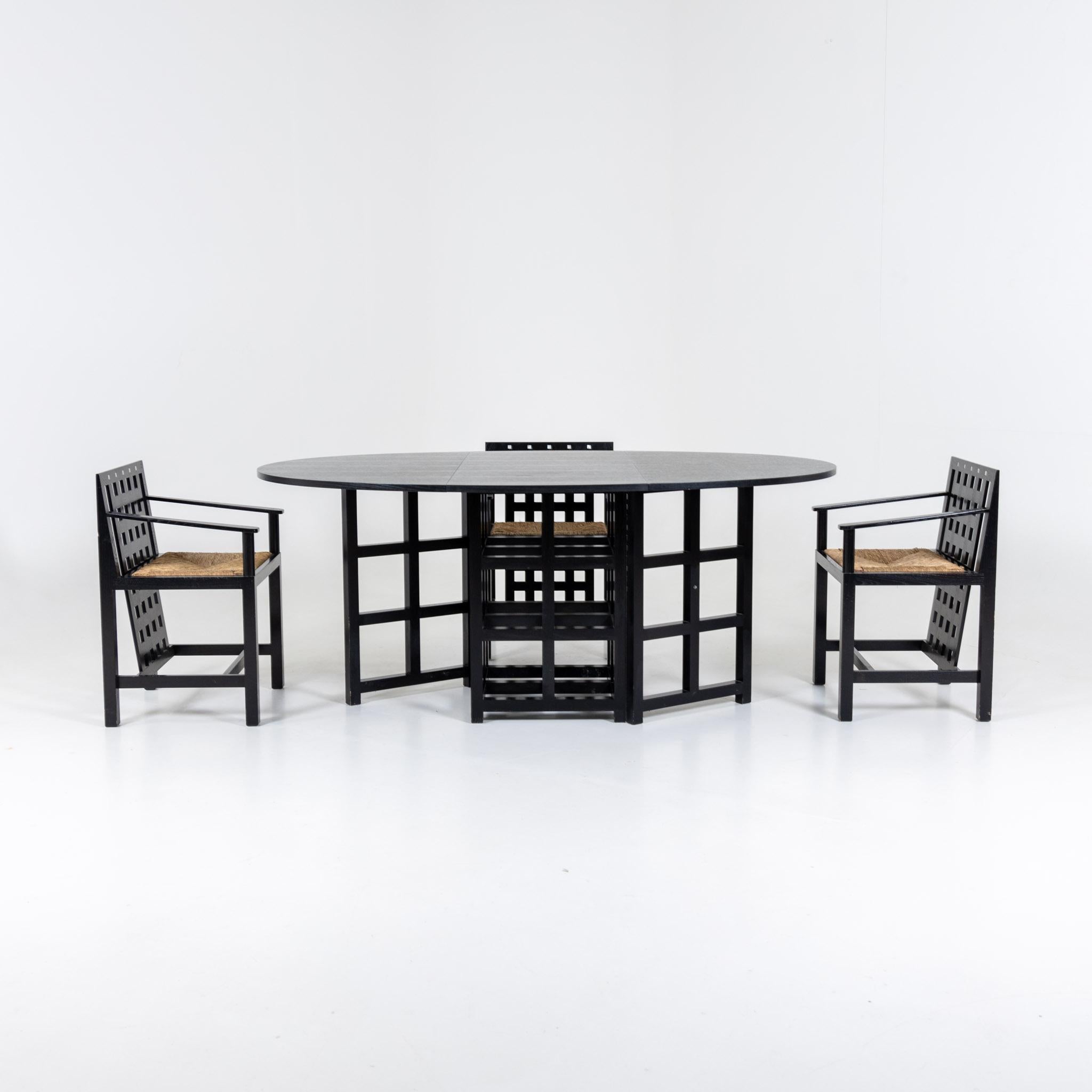 Four black lacquered armchairs and folding dining table designed by Charles Rennie Mackintosh in 1918 and produced by Cassina since 1975. The seats are made of raffia wicker. Stamped on the bottom Cassina / Charles Rennie Mackintosh. Dimensions