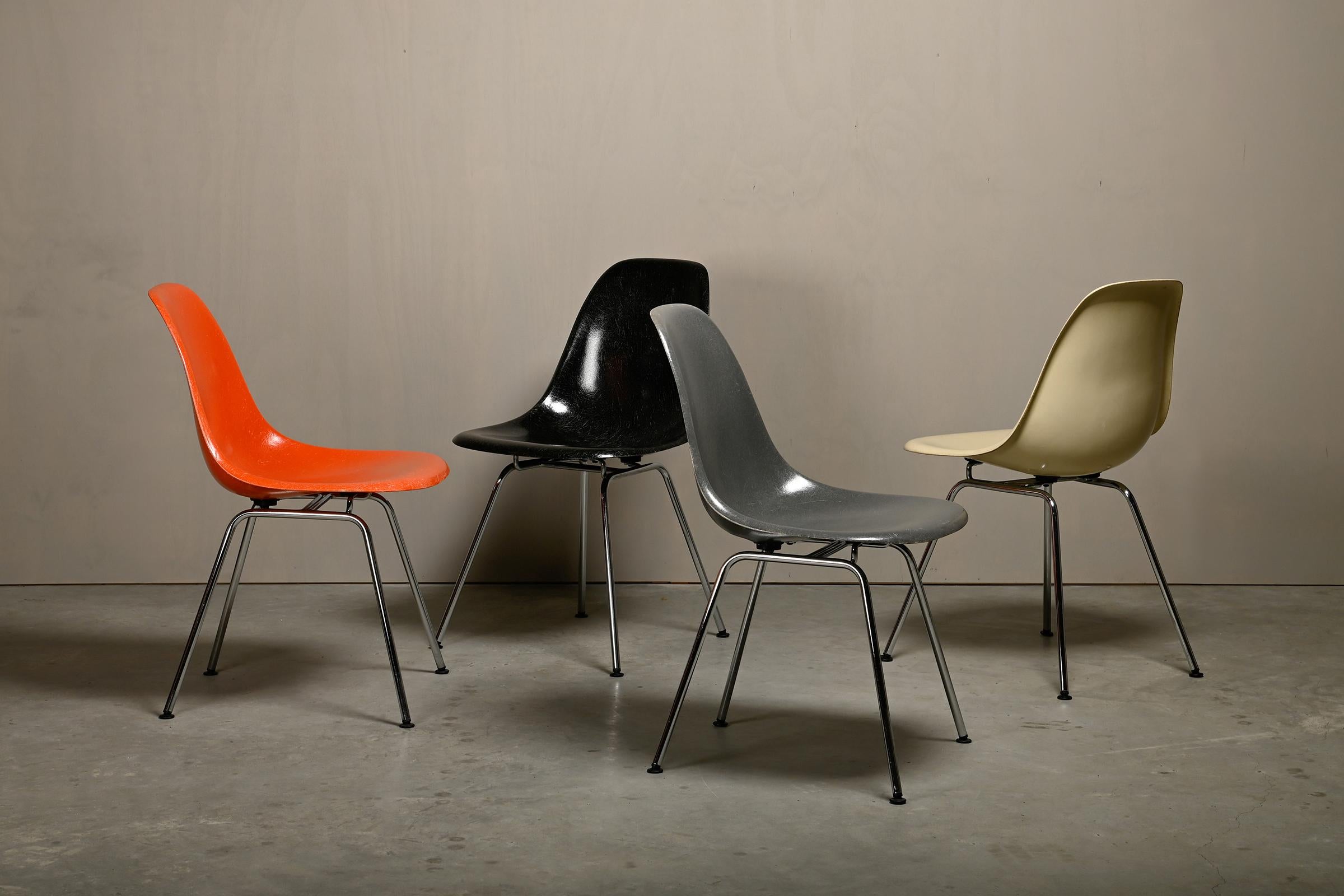 Iconic side chairs designed by Charles and Ray Eames for Herman Miller / Vitra. Molded fiberglass shells in the colours: Parchment, Red Orange, Elephant Hide Grey and Black. Assembled on vintage chrome plated steel H-bases. The chairs are in very