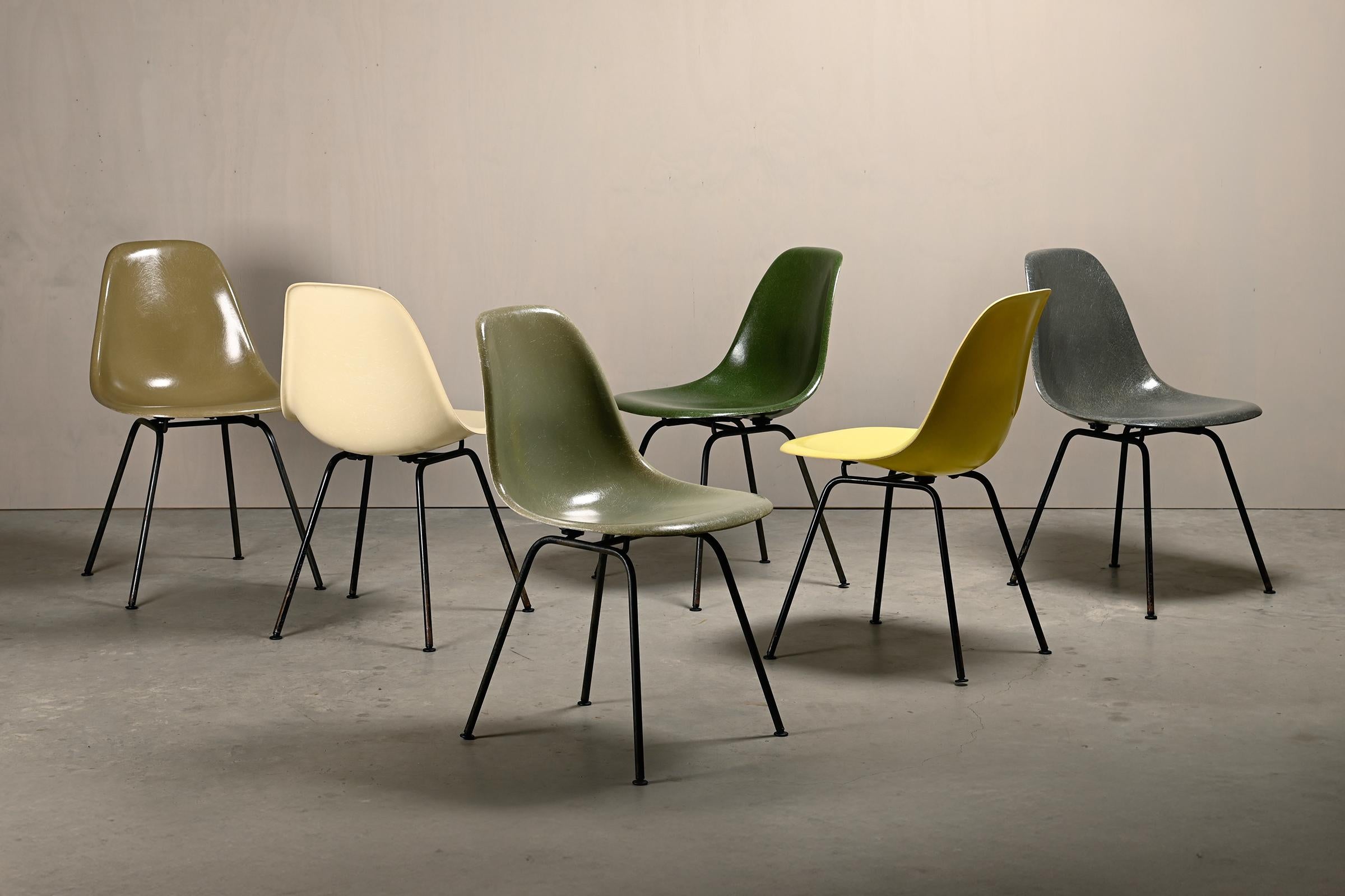 Ikonische Stühle, entworfen von Charles & Ray Eames für Herman Miller. Geformte Glasfaserschalen in den Farben: Elephant Hide Grey, Pergament, Lemon Yellow, Raw Umber, Olive Green Dark und Sea Foam Green. Montiert auf H-Sockeln aus schwarzem Stahl.