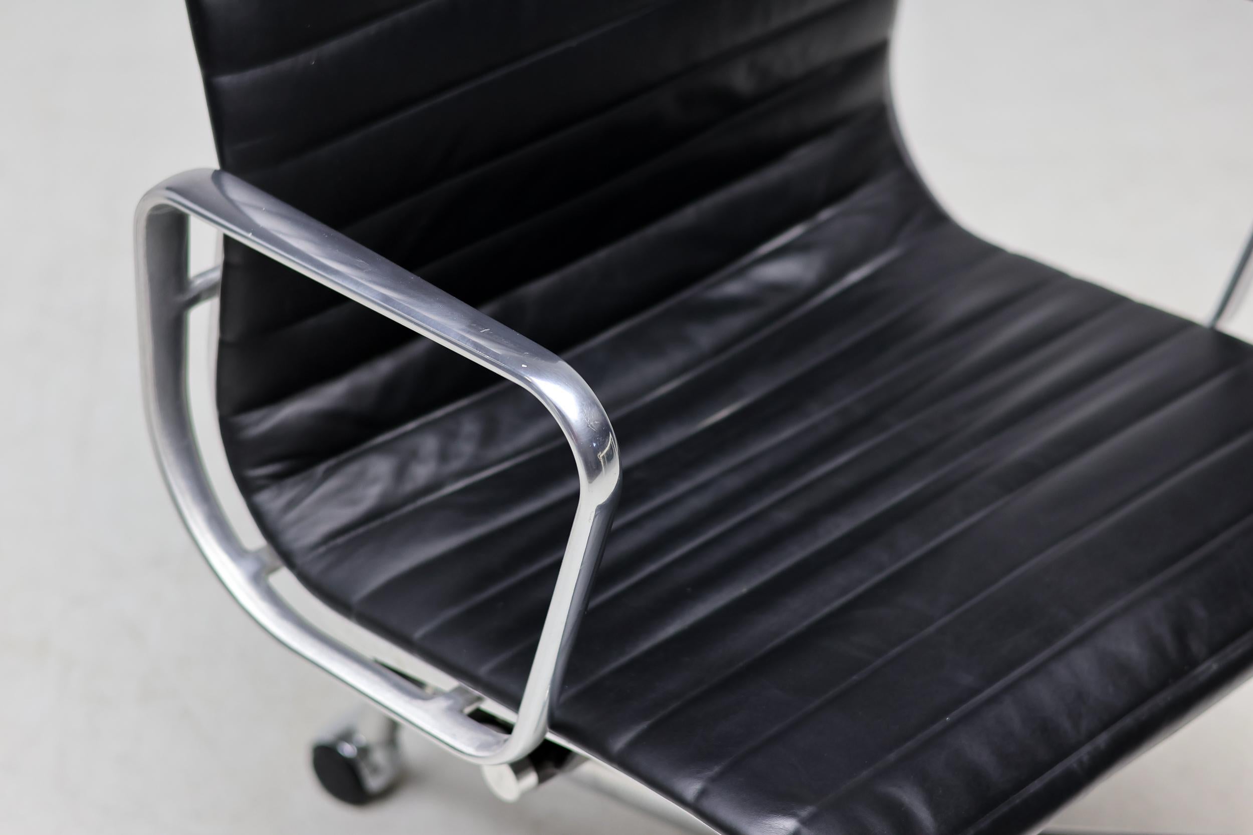 Silla de oficina ejecutiva, modelo EA119, en EE.UU. conocida como EA337, diseñada por Charles and Ray Eames para Herman Miller. Respaldo y asiento de cuero negro, tanto delante como detrás. Armazón, reposabrazos y base de cinco radios de aluminio