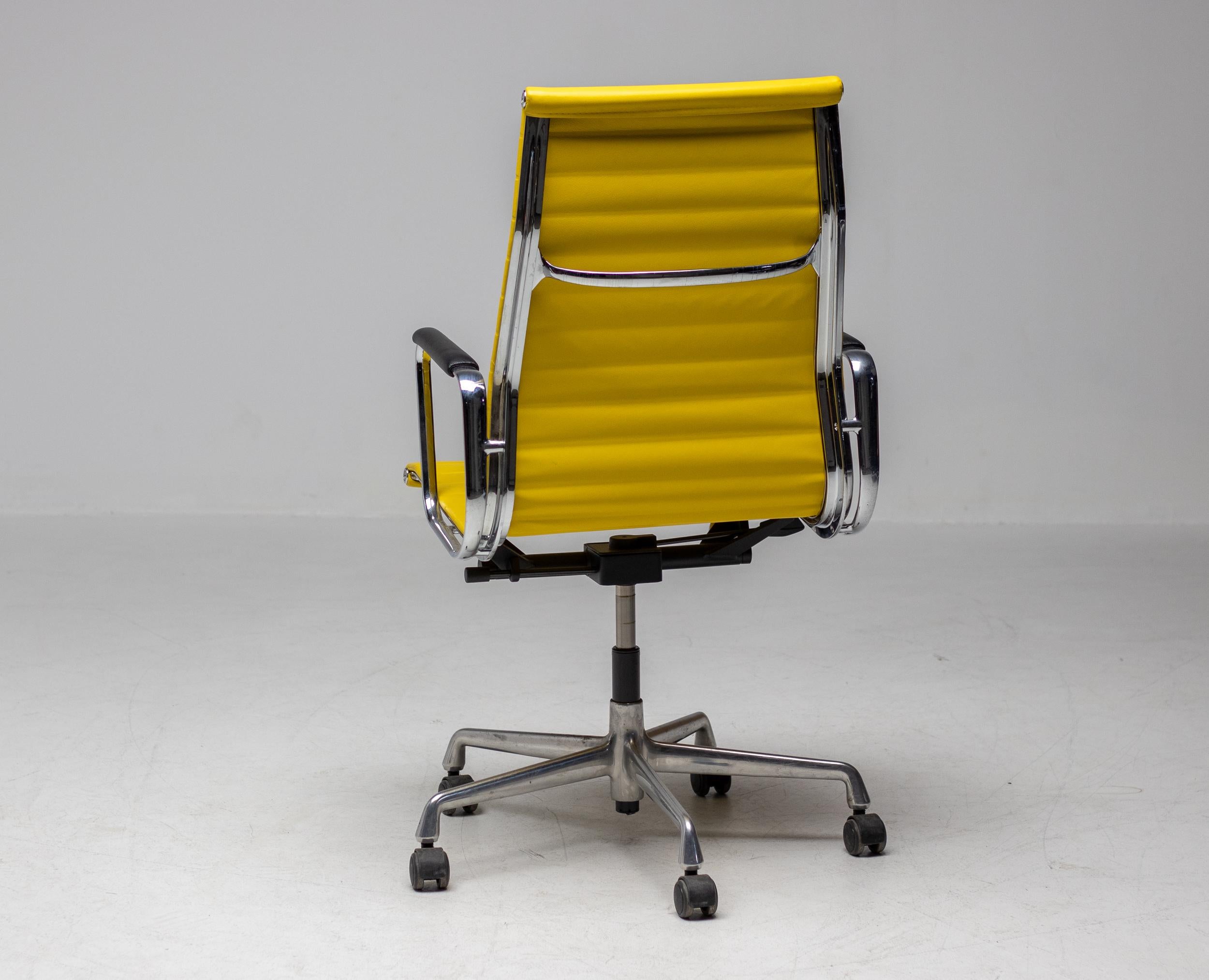 Executive office chair, model EA119, designed by Charles and Ray Eames for Vitra / Herman Miller. 
High backrest and seat in striking yellow Naugahyde. Frame, armrests and five-star base in die-cast aluminium. Seat mechanism with adjustable