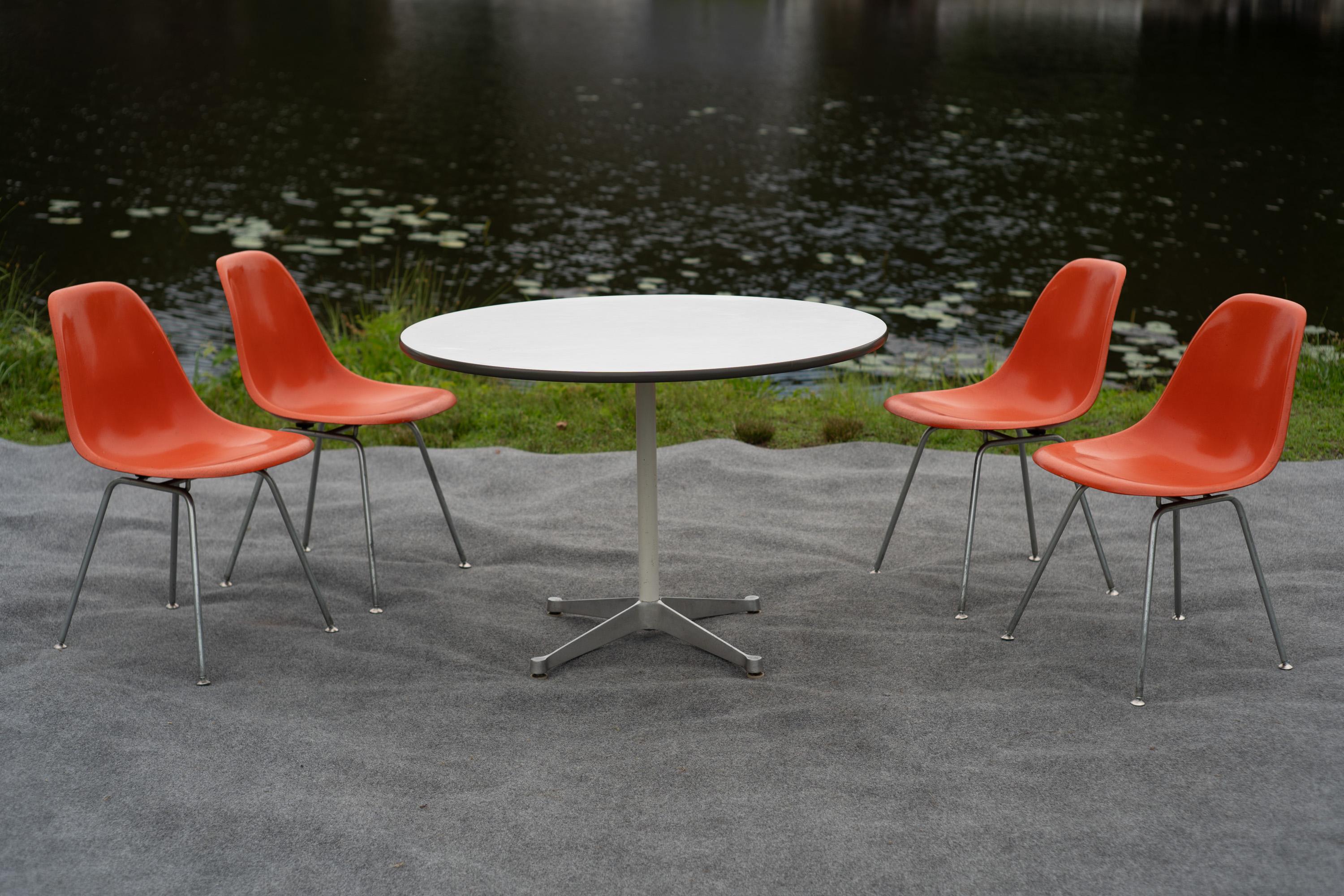 Diseñado por los legendarios Charles and Ray Eames, este juego de comedor fue fabricado en la década de 1970 por Herman Miller. Este conjunto consta de 4 sillas DSX con carcasas de color naranja brillante y bases metálicas, y la mesa de comedor