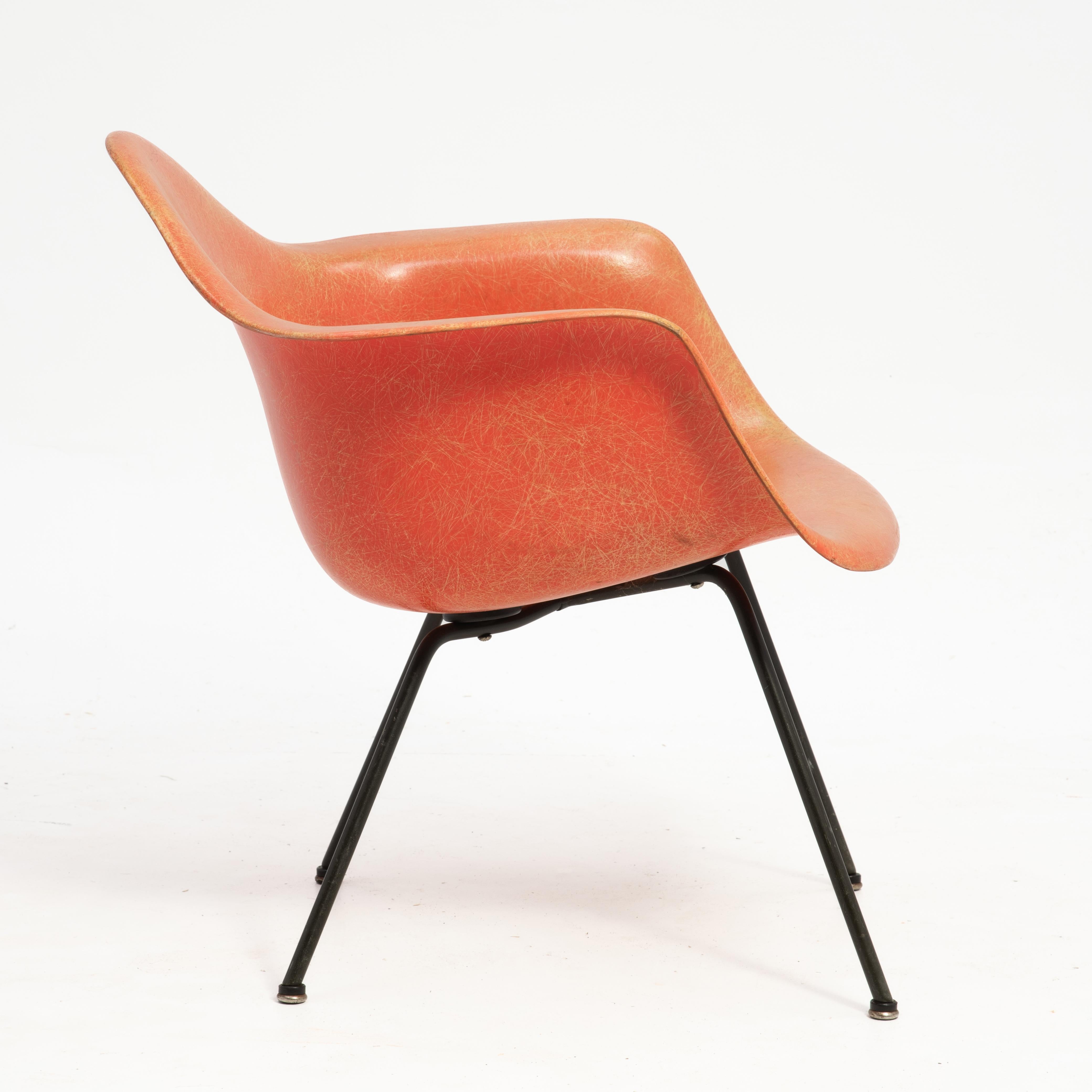 A fabulous Charles & Ray Eames transitional armchair produced by Herman Miller with Zenith Plastics. The salmon colored LAX chair features a rope edge, X base, large shock mounts, boot glides and the checkerboard label. (The checkerboard label was
