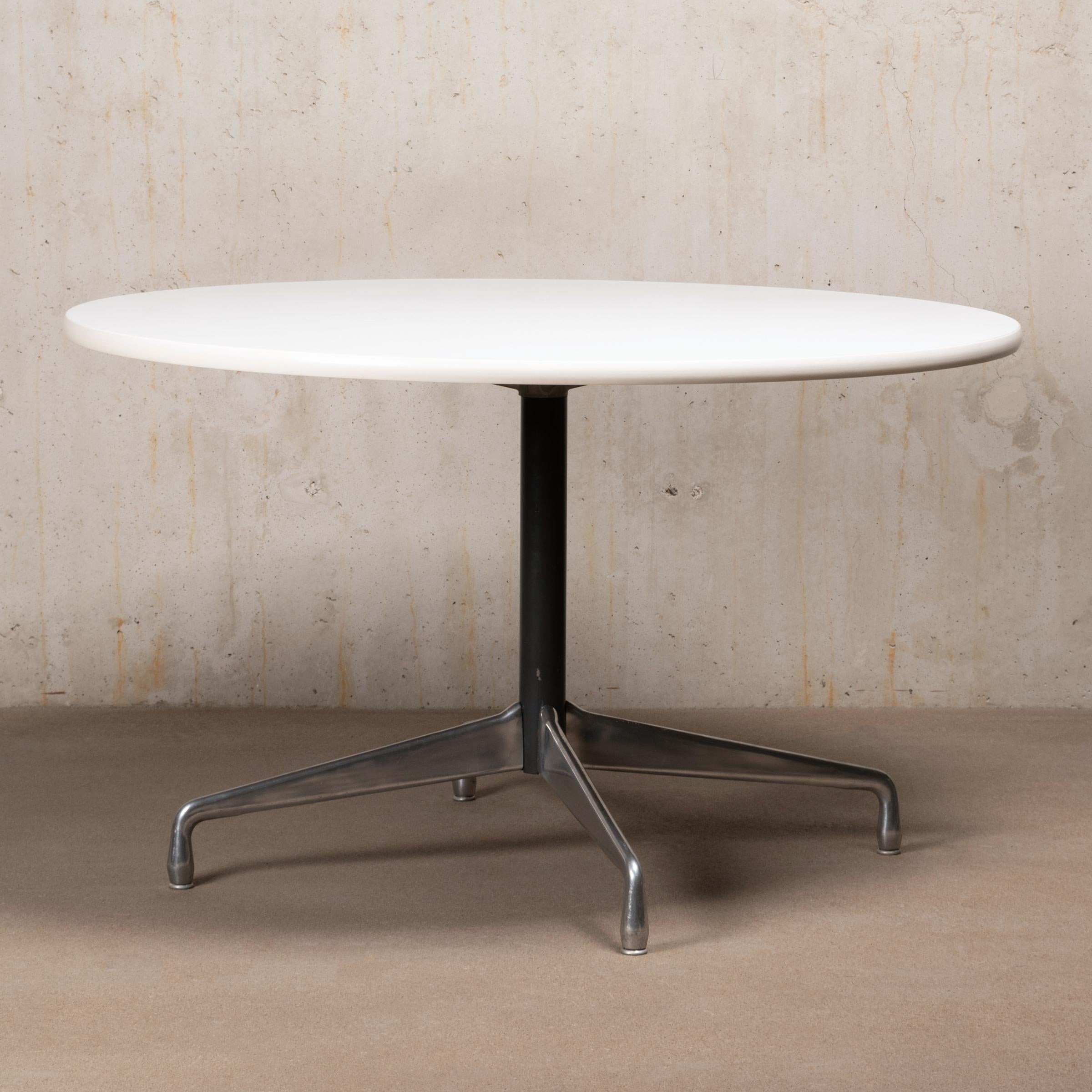 Early dining table by Charles and Ray Eames for Herman Miller. Chrome plated cast aluminum base with (height) adjustable glides and white laminated table top with rubber edge. The tabletop has a diameter of 122 cm (47 3/4 inch), suitable for 4