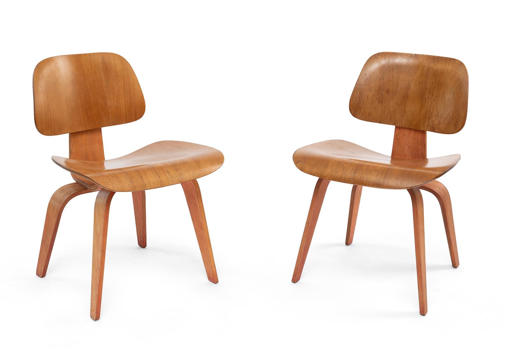 Early and rare pair of two tone Eames for Evans DCW chairs. These examples are first generation and have original red aniline dyed legs and knecks. Shock mounts have been replaced by Hume Modern. Price listed is for the pair.