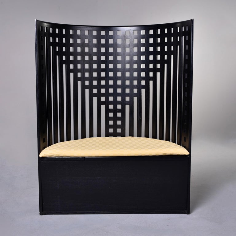 Designed in 1902 for the Willow Tea Room in Glasgow, the Willow Chair by Charles Rennie Mackintosh is a stunning statement piece with a tall, curved lattice back and storage area beneath bench. Handcrafted of ash and stained black in Italy. This one