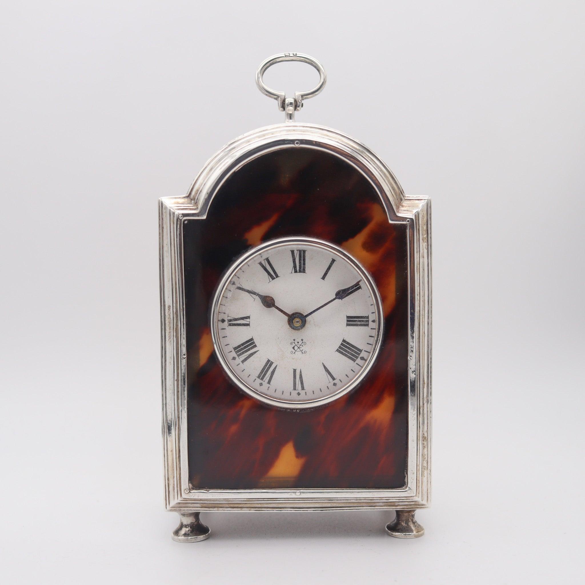 Desk table clock designed by Charles & Richard Comyns.

This is a beautiful desk clock created by the top notch and prestigious silversmith company of Charles & Richard Comyns. The case was designed in a rectangular shape with a curved pediment with