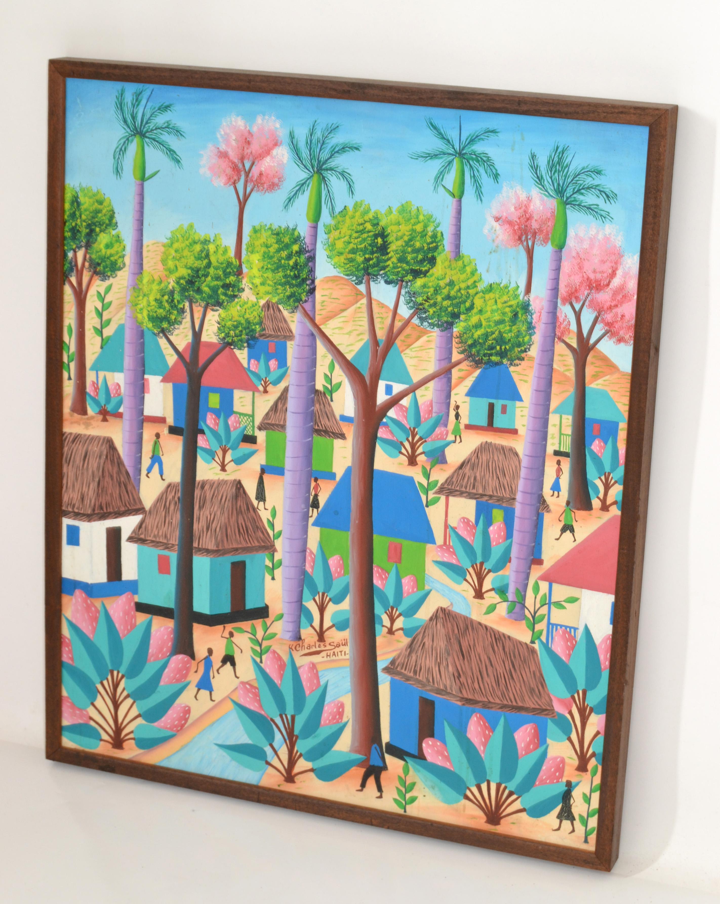 Une peinture originale encadrée à l'acrylique sur toile d'une scène de village haïtien avec des gens qui vont et viennent, des huttes, et de grands feuillages et palmiers. 
Signé par Charles Saül (Haïtien, 1943 - ), et fabriqué en Haïti dans les