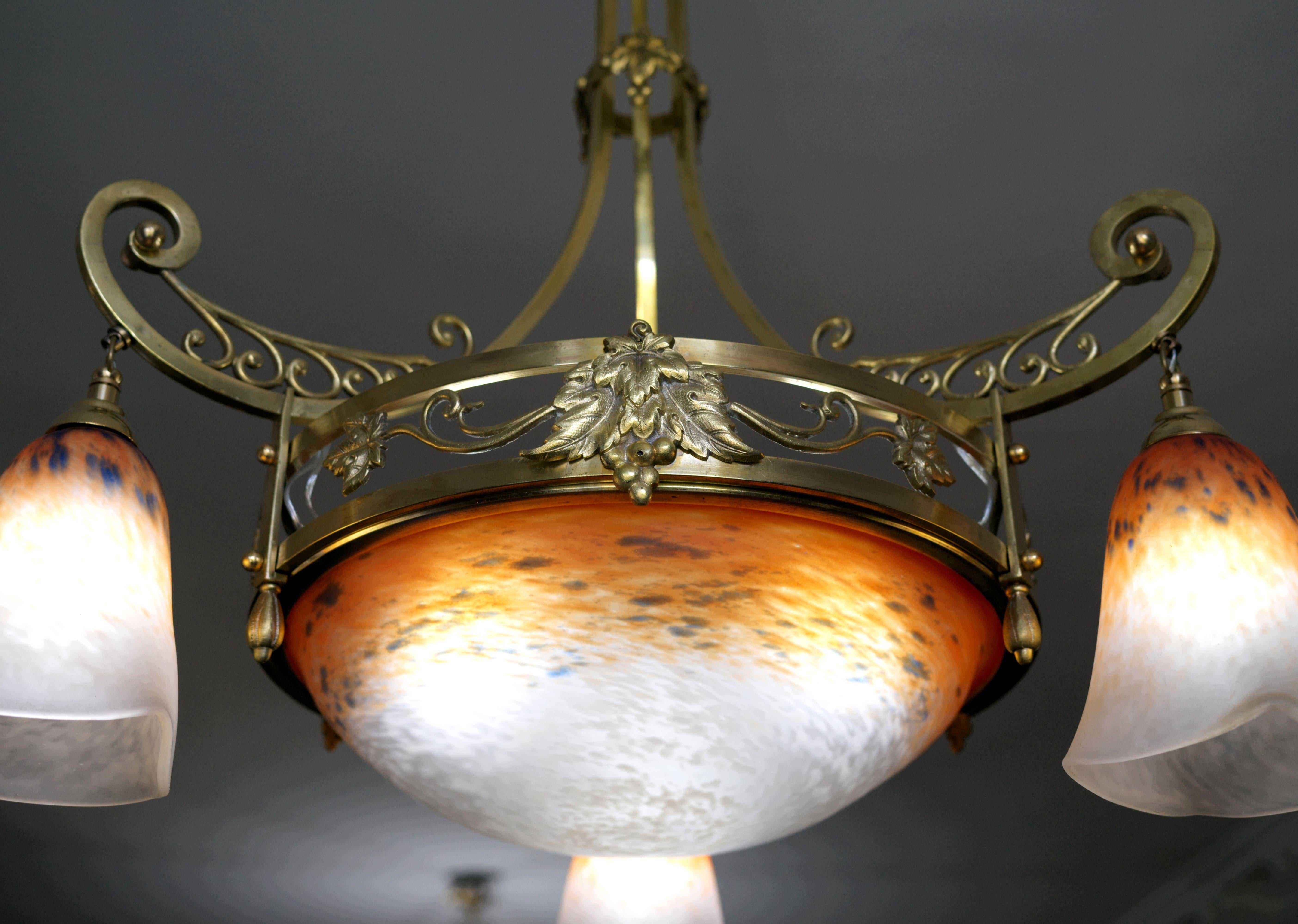 Esta lámpara francesa Art Déco fue diseñada por Charles Schneider en Epinay-sur-Seine, París, en la década de 1920. Presenta exquisitas tulipas de cristal moteado, con polvos aplicados entre dos capas de cristal, que cuelgan graciosamente de su