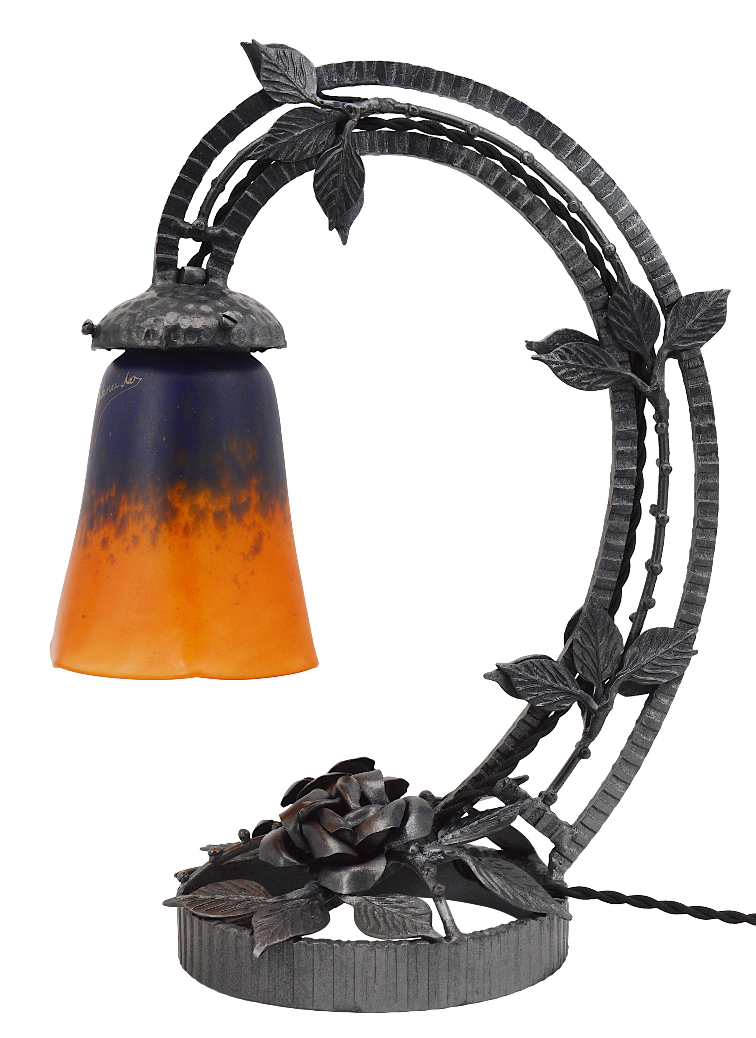 Lampe de table Art déco française par Charles Schneider, Epinay-sur-Seine (Paris), années 1920. Abat-jour en verre tacheté, des poudres sont appliquées entre deux couches, qui vient se suspendre à son superbe socle en fer forgé. Hauteur :