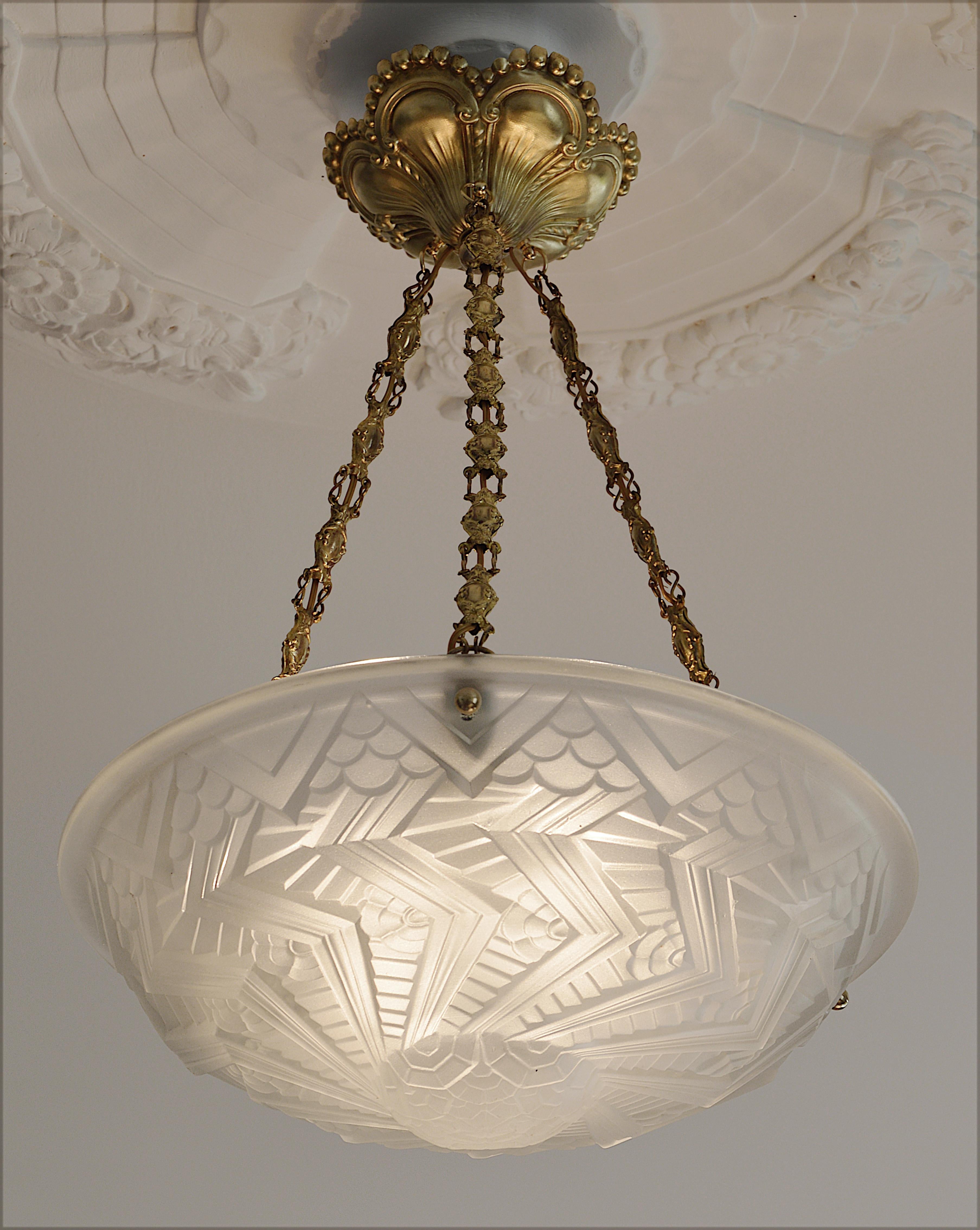 French Art Deco chandelier by Charles Schneider, Epinay-sur-Seine (Paris), France, circa 1925. Molded glass shade with a stylized geometric pattern and sharp edges that comes hung at its original stamped brass fixture. A great work by Schneider