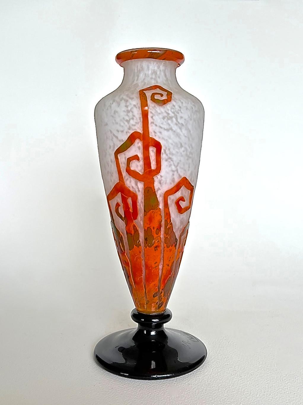 An elegant Art Déco cameo glass vase of baluster form with applied deep violet glass foot. The mottled white ground is textured and overlaid with mottled orange and green. It is then acid-etched and wheel carved with a highly stylised design of fern