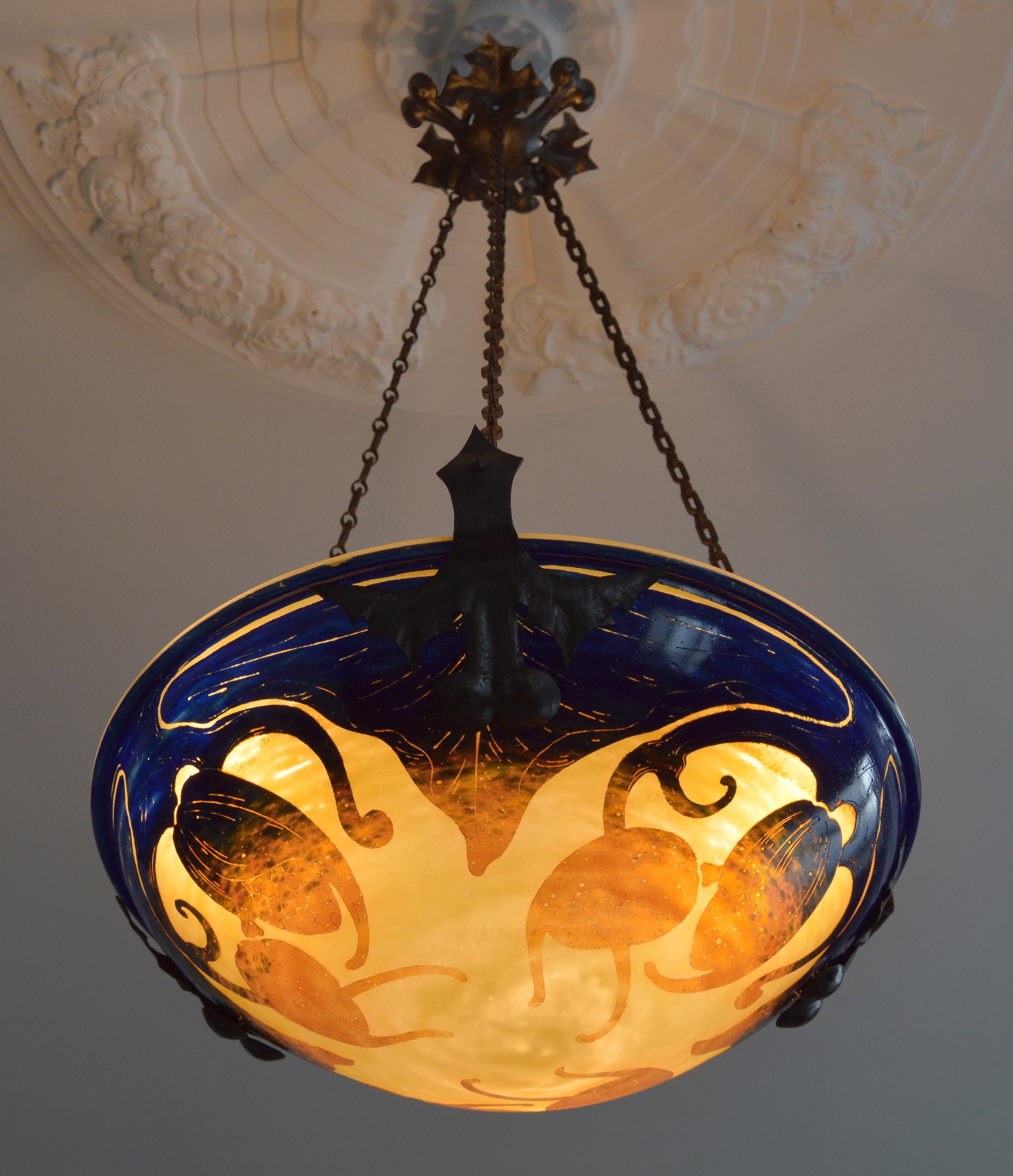 French Art Deco chandelier by Charles Schneider, Epinay-sur-Seine (Paris), 1922-1925. Yellow glass overlaid with orange changing to blue at the top. Houblon pattern acid-etched that comes hung at its genuine and elegant wrought iron fixture by