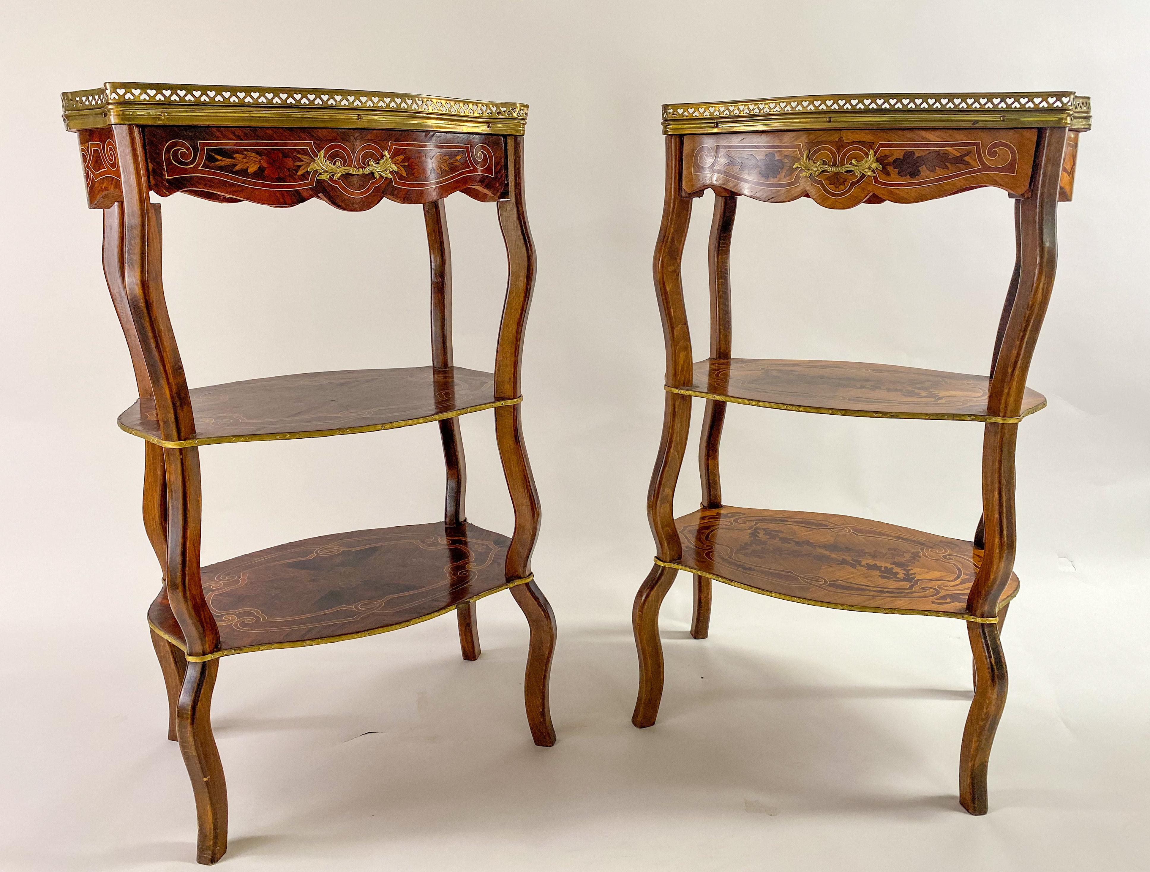 An elegant compatible pair of French Transitional style three-tiered marquetry inlaid side , end or serving tables in the manner of the Charles Topino, cabinet maker (French, 1742–1803 Paris). Expertly carved of quality tulip wood, each table