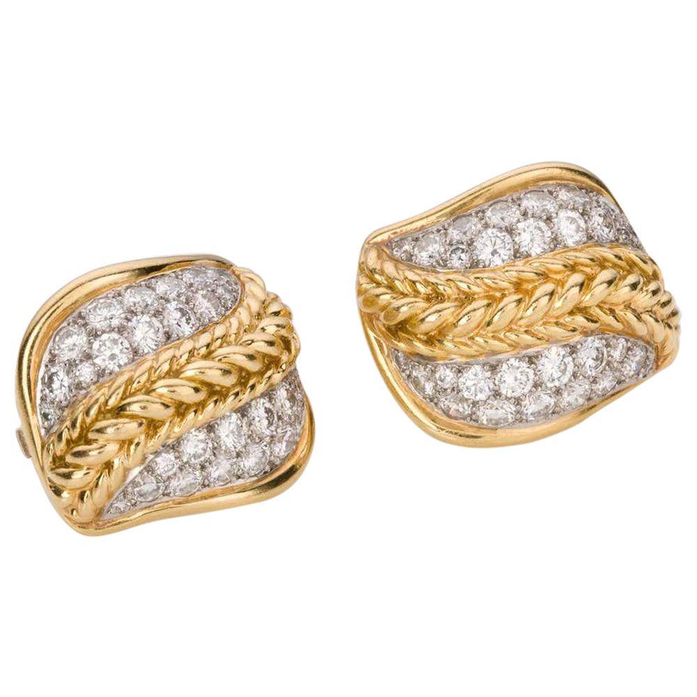 A beautiful pair of platinum & 18k yellow gold ear clips, set with 60 pave set modern brilliant cut white diamonds estimated as G colour, SI clarity in a stylised leaf shape with a woven yellow gold detailed centre. The approximate total weight of