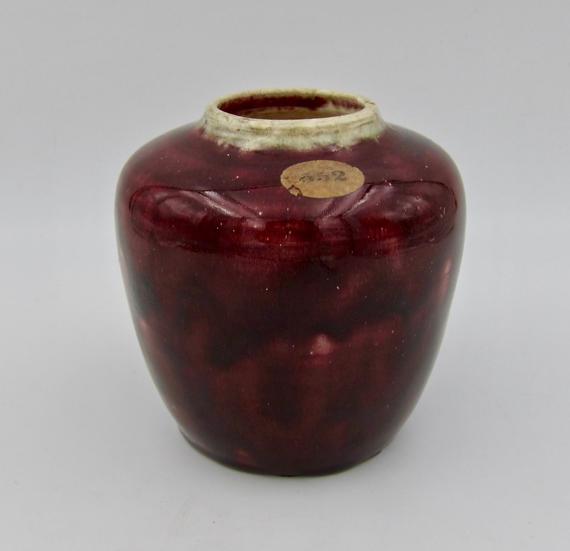 An early 20th century Arts & Crafts vase by American painter, engraver, sculptor, and ceramicist, Charles Volkmar (1841-1914). This diminutive art pottery vessel was hand-raised and decorated with a dark, mottled coppery-red glaze and a contrasting