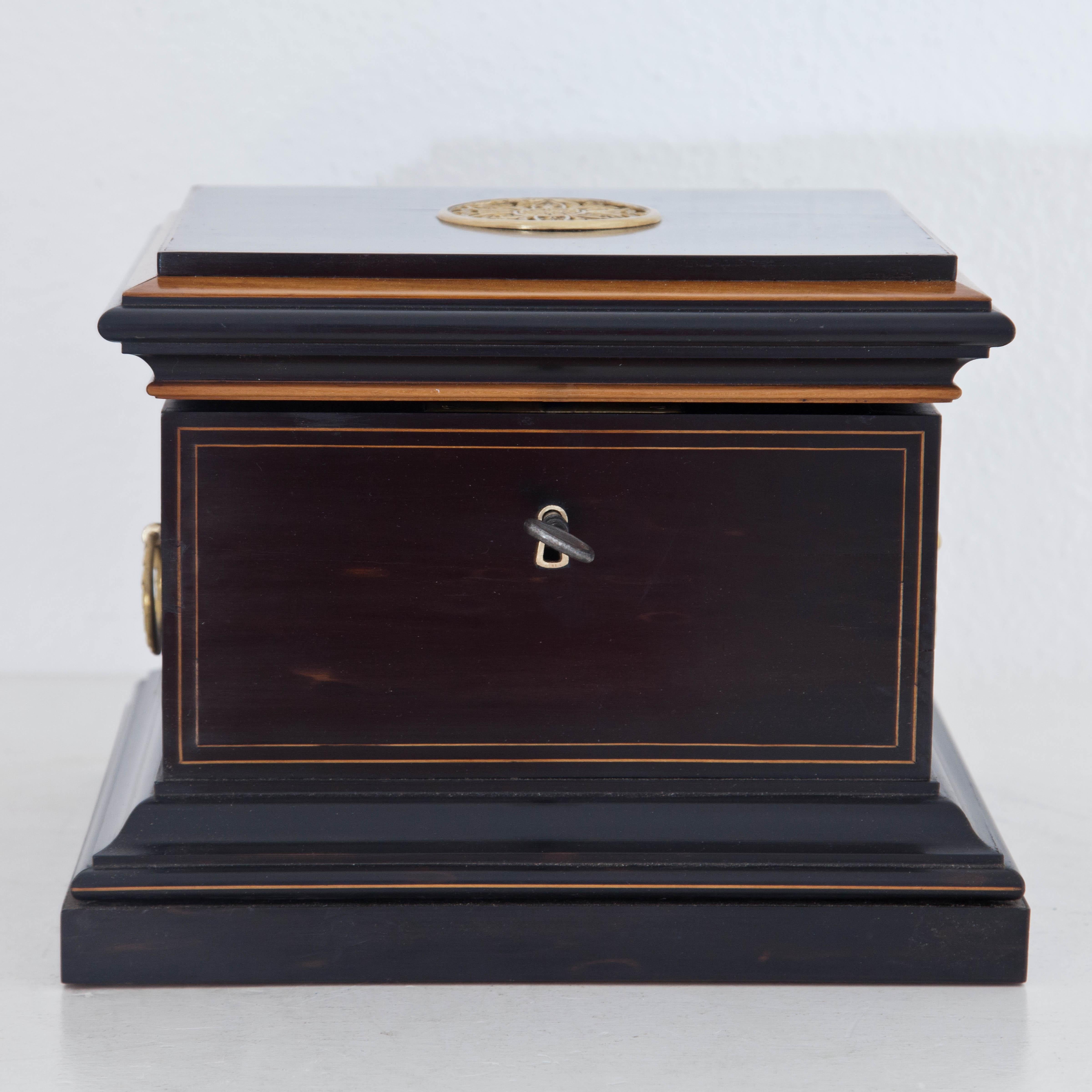 Rectangular casket with thread inlays and handles standing on a wide profiled Stand and rosette ornament in fire-gilt bronze. Inside lined with wallpaper and secret compartment under the floor.
  