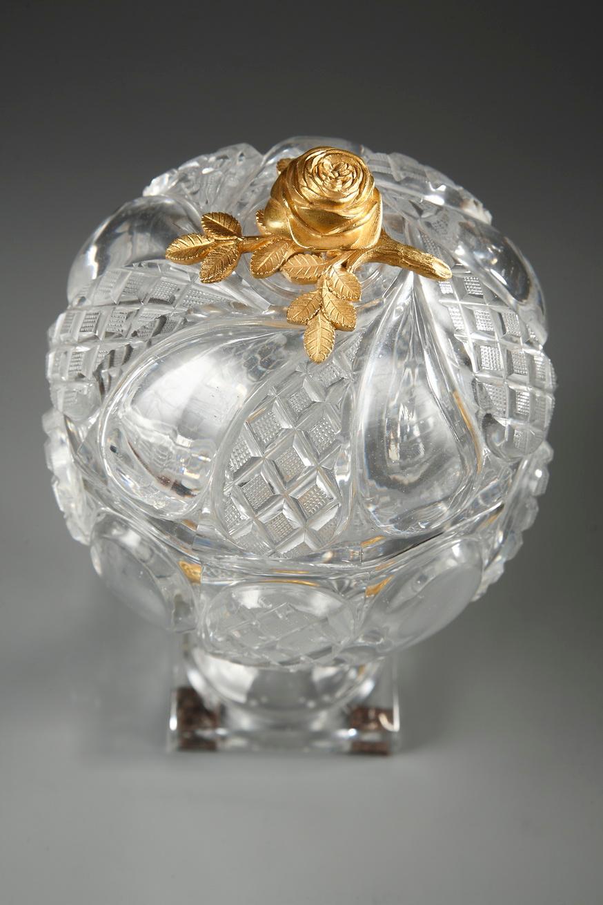 A cup in Baccarat cut-crystal with fine twisted patterns alternating with twisted diamond-shaped patterns in high relief. The lid is topped by a gilt bronze rose. Foot adorned with an ormolu ring, chiselled with flowers, resting on a small square
