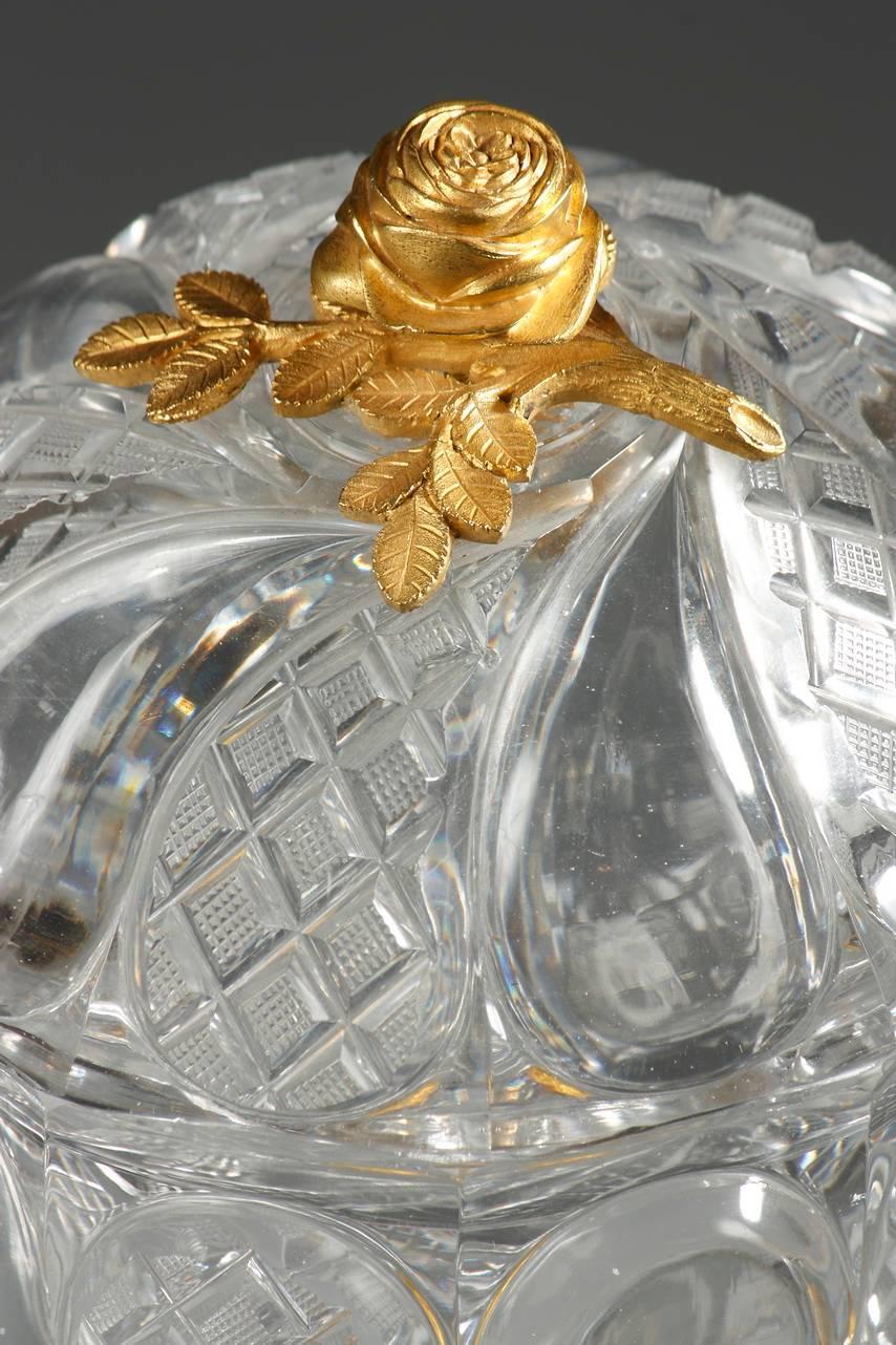 Goblet in Baccarat cut crystal featuring large, smooth, curved teardrops that alternate with teardrops chiseled with diamond patterns in high relief. The lid is topped by a gilt bronze rose, and an ormolu ring, engraved with flowers, connects the