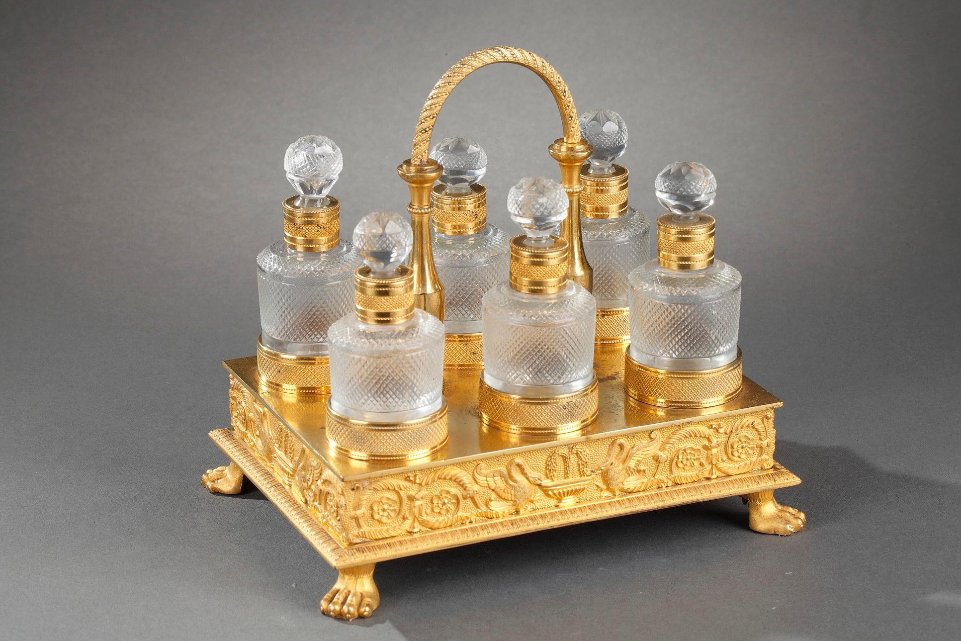 Cellaret en cristal taillé et en bronze doré, fait à la main, comprenant six flacons à parfum et leurs bouchons ornés de motifs géométriques et de rosettes. Le plateau rectangulaire en bronze doré est décoré d'une frise admirablement travaillée. La