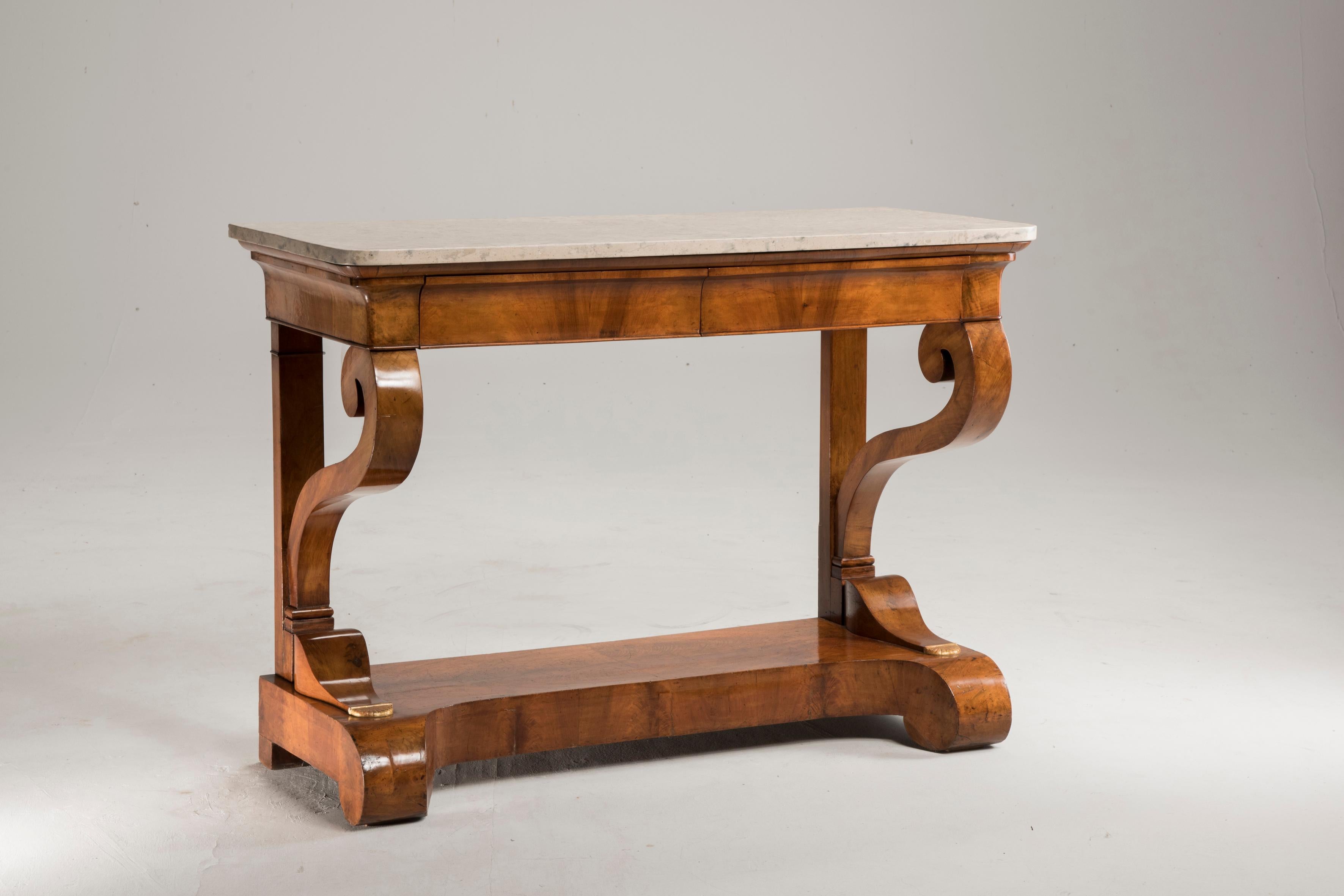 Charles X early 19th century walnut wood marble-top table console, from France, from period 1810-1820. The walnut wood is light color, the marble is around grey. The table features two drawers on the front side just below the marble top. We have