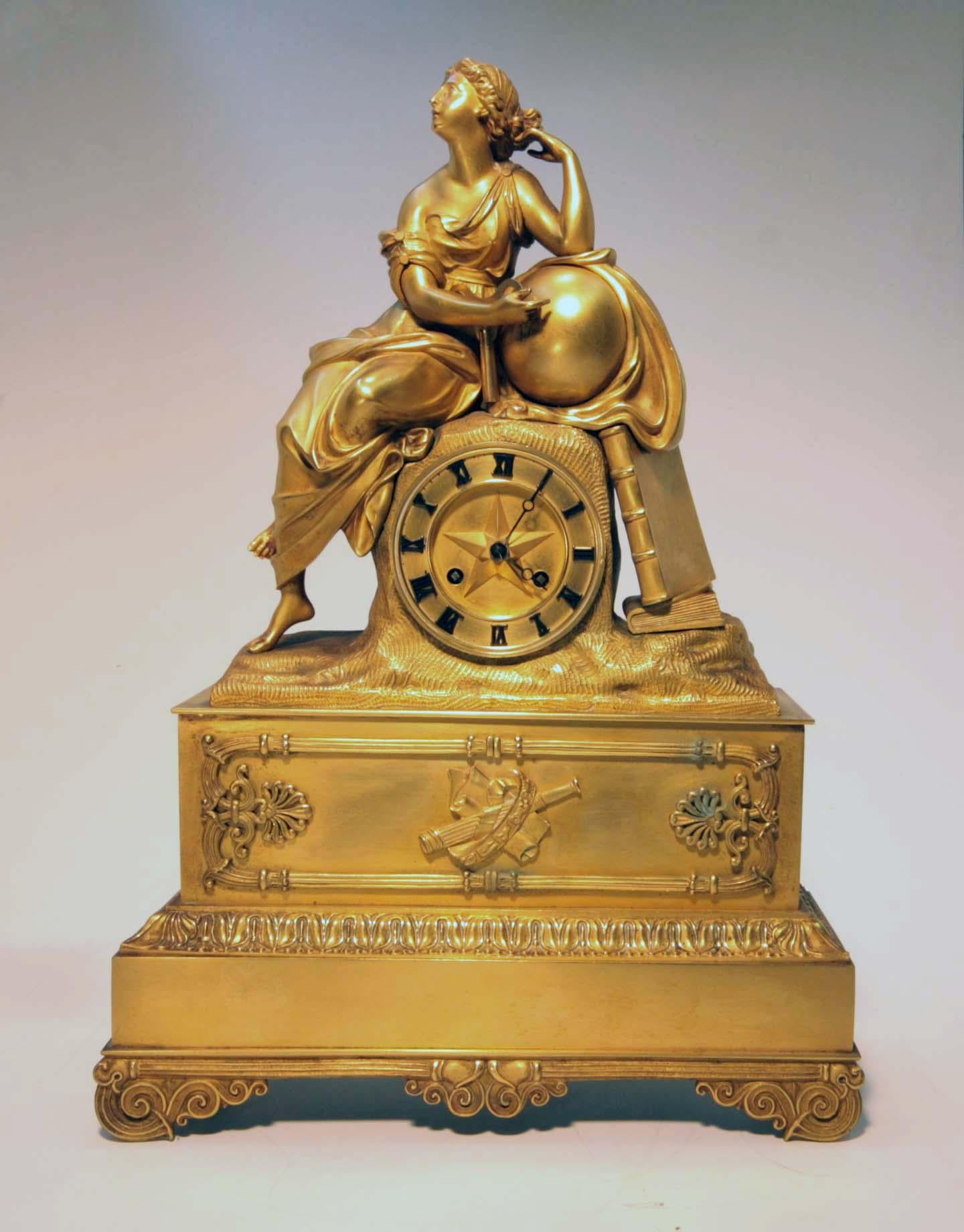 This elegant clock is distinguished by its crisply modeled subject and the extraordinary completeness of its original finish. The seated figure is of Urania, muse of astrology, leaning on a globe. The clock face is centered by a raised star