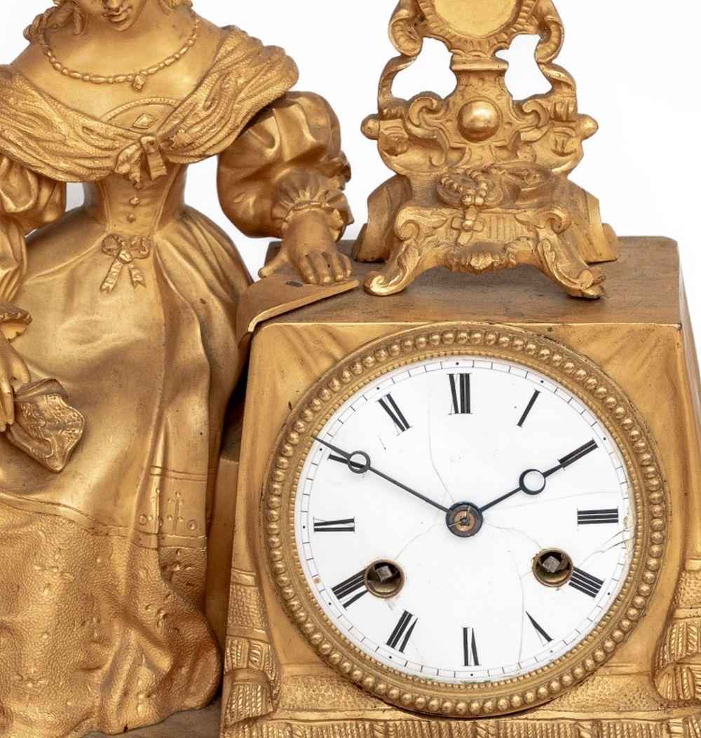 Charles X Gilt Bronze Figural Mantel Clock, circa 1830, the circular enamel dial with strike on bell movement, surmounted by a seated figure of a woman at her dressing table, on a rectangular plinth with scrolled feet.  17