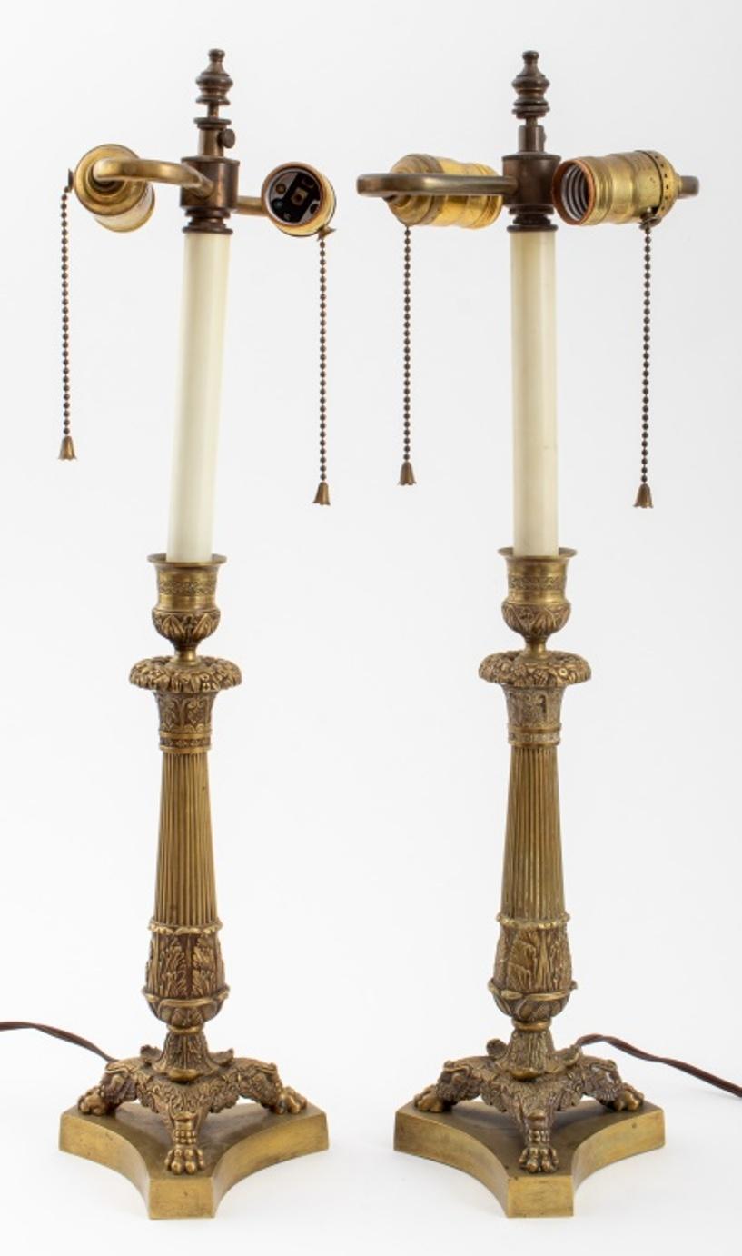 Pair of Charles X gilt metal candlesticks, mounted as lamps, with Gothic Revival candle holders above floral wreath-mounted capitals on fluted columns above three lion paw feet on in-curving conforming bases.

Dimensions: 22