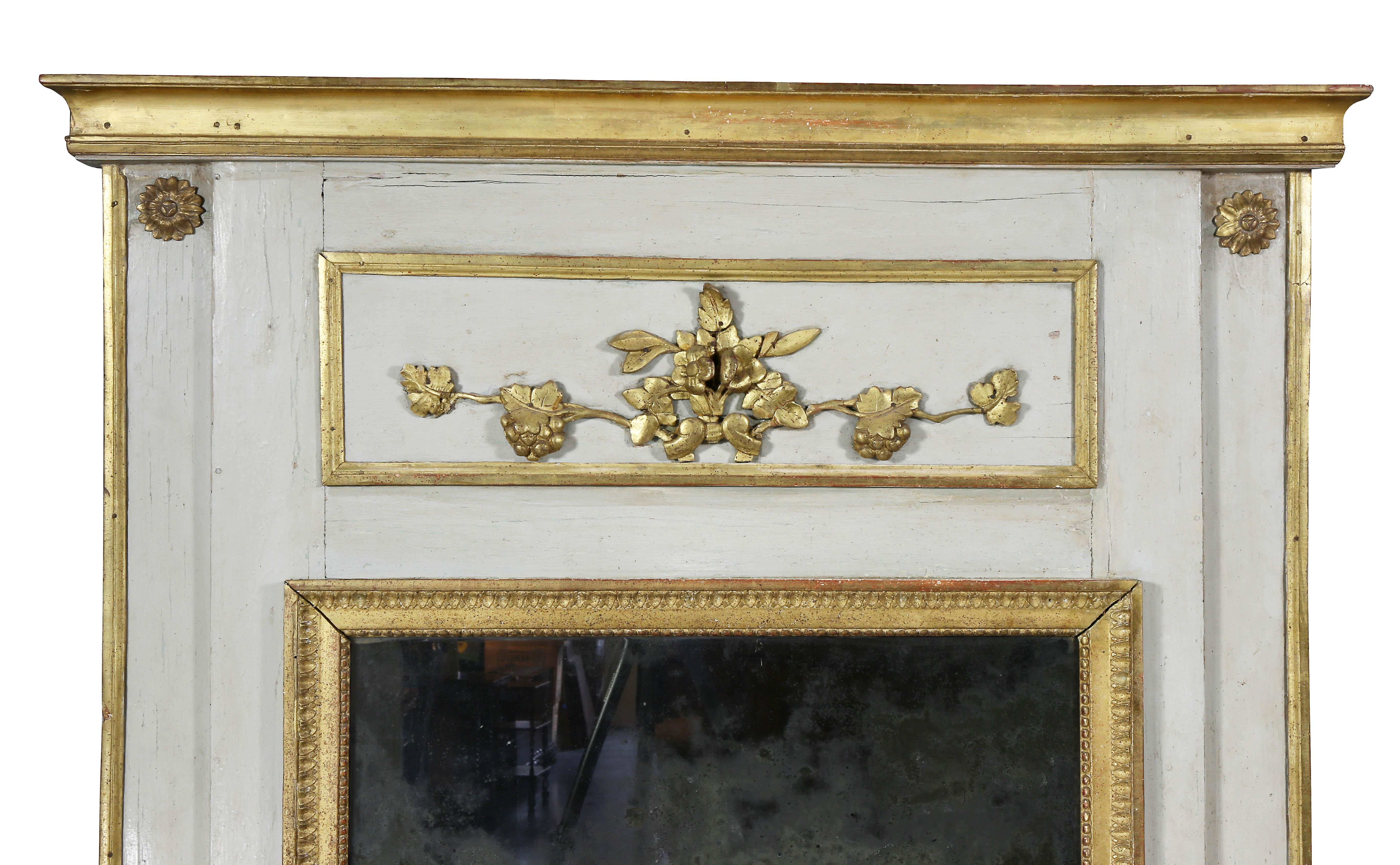 Rectangular molded cornice over a panel with floral and grape carving over a mirror plate with gilded edge and painted surround.