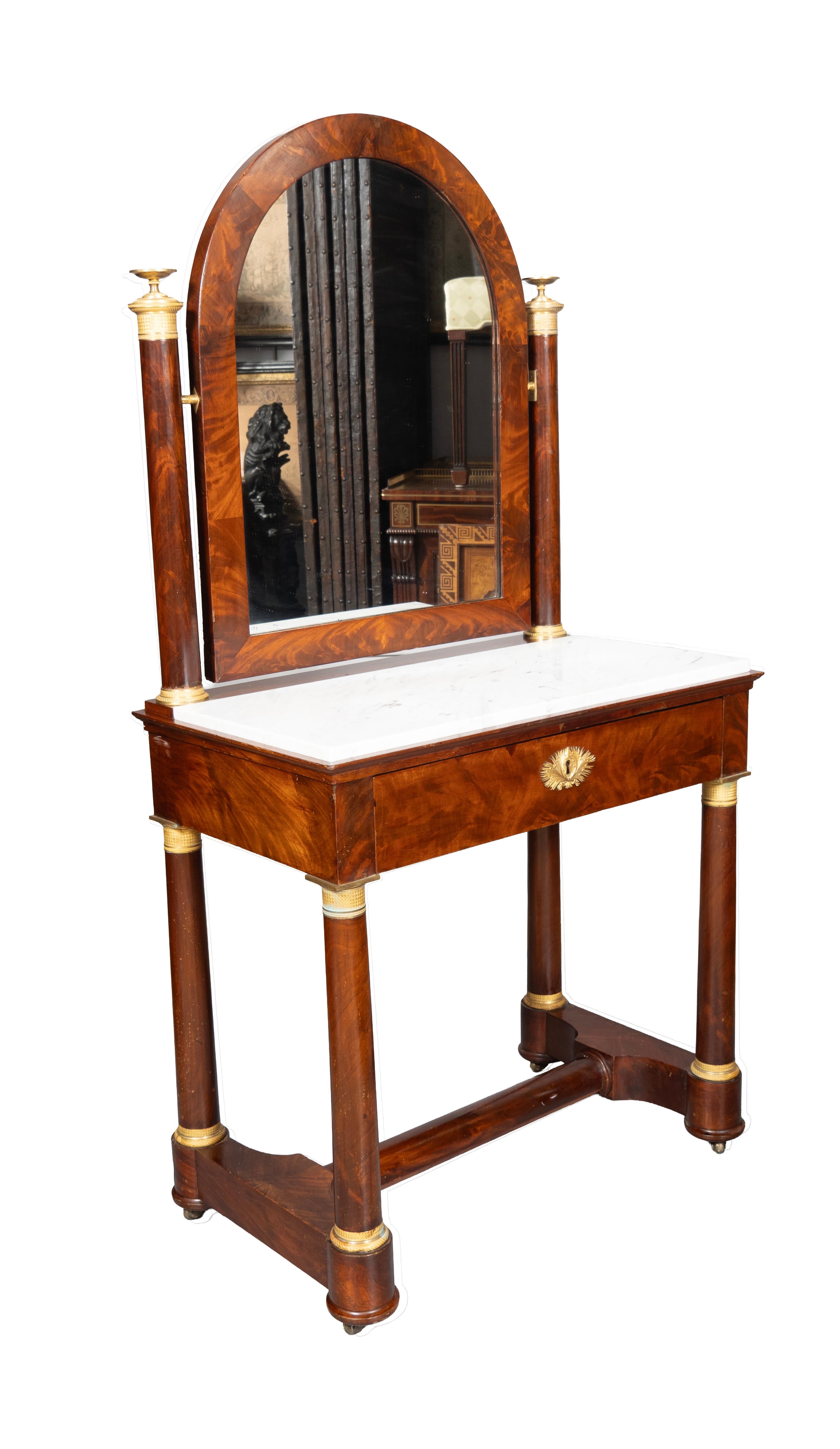 With arched adjustable mirror in mahogany surround. with cylindrical posts with ormolu capitols. The base section with a white marble top over a drawer with escutcheon opening to a fitted interior with green tooled leather. Cylindrical legs with