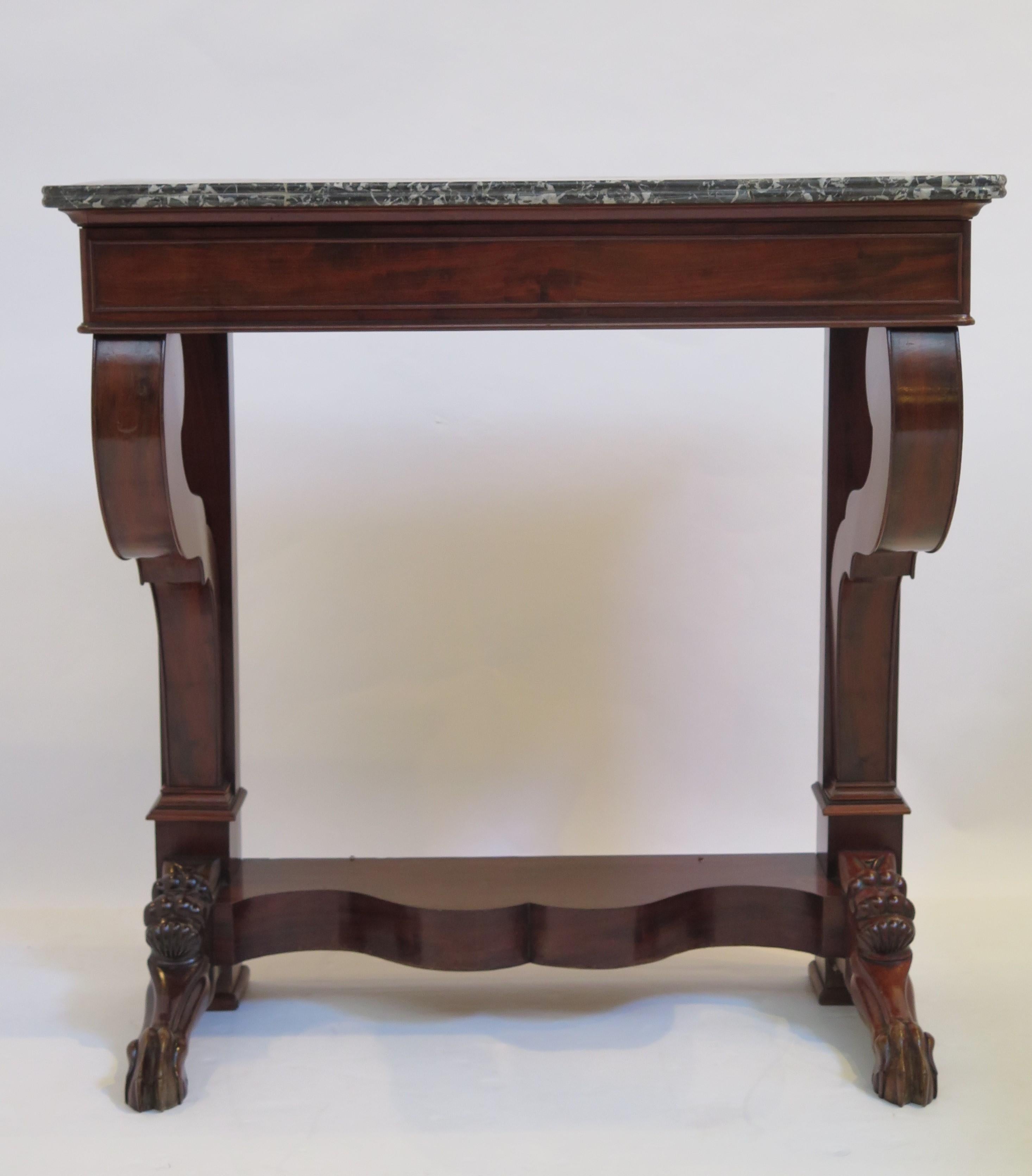 Charles X mahogany console, with a Sainte-Anne grey marble top over the single drawer. The scroll supports on a shaped base are raised on paw feet.