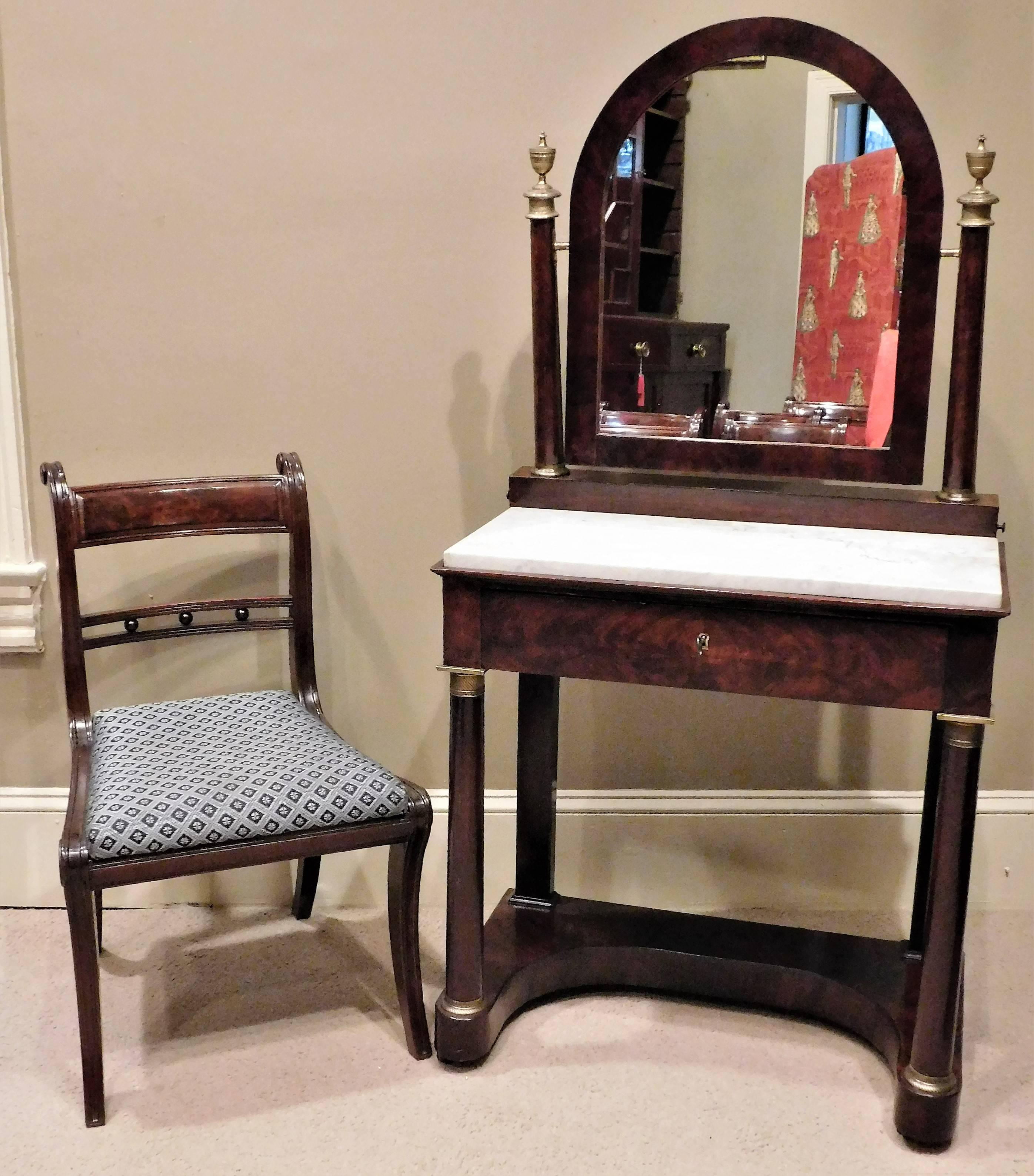This Empire dressing table has a marble top and ormolu (gilt brass) mounts and knobs. The piece is French polished mahogany and figured mahogany veneer with oak secondary wood. The table has one large drawer with dividers and two long candle drawers