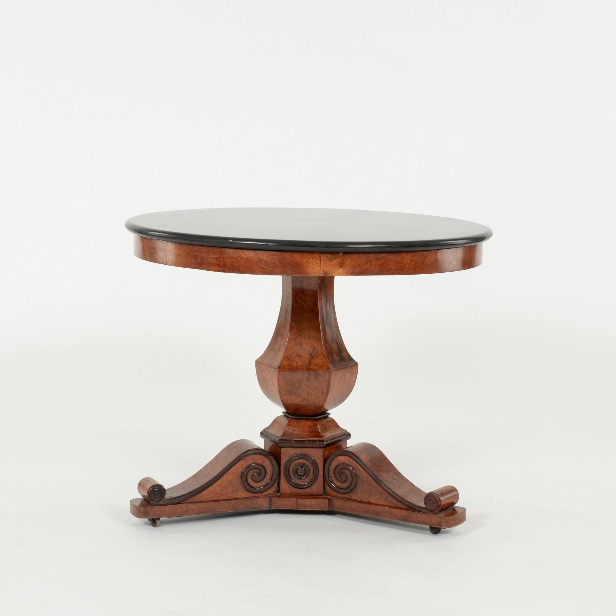 A handsome period Charles X center table with black marble top over pedestal base on casters.