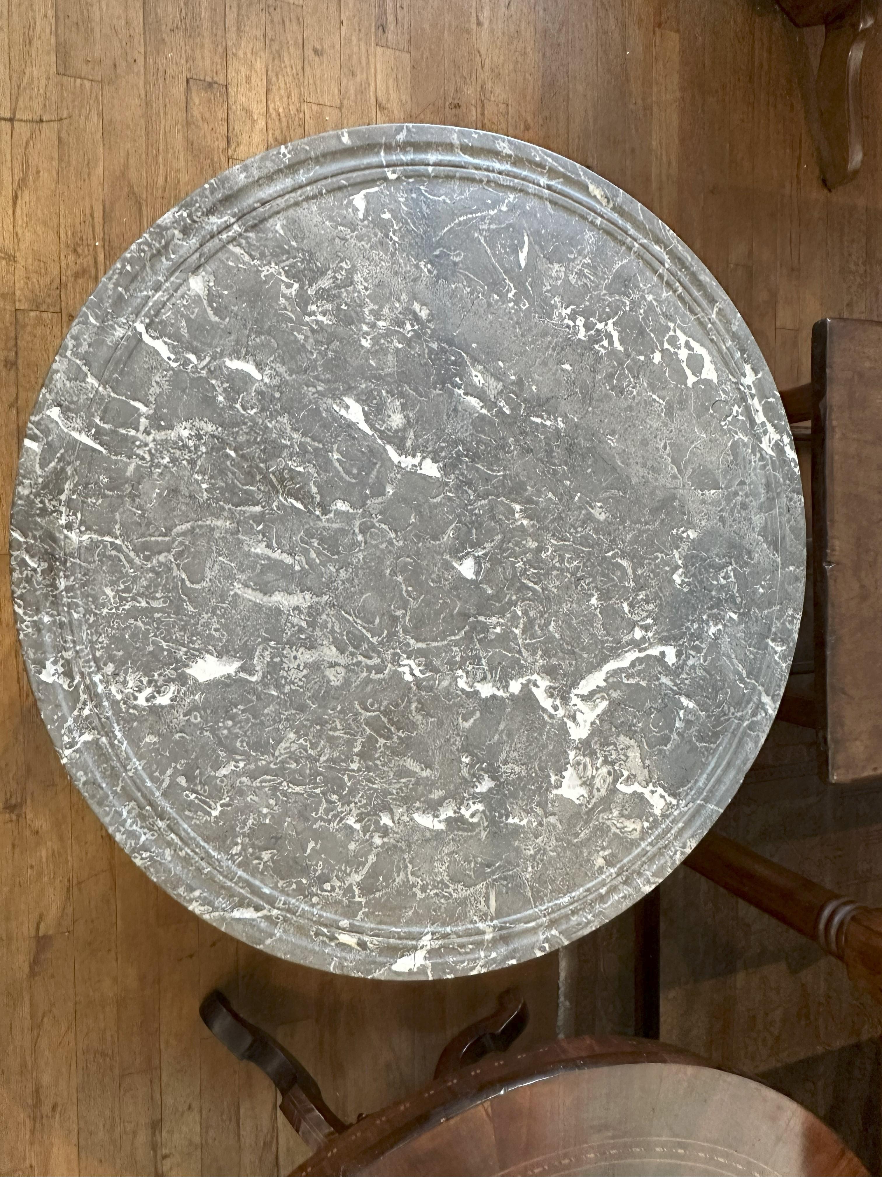 Circular marble top raised on a incurving triangular base ending in paw feet