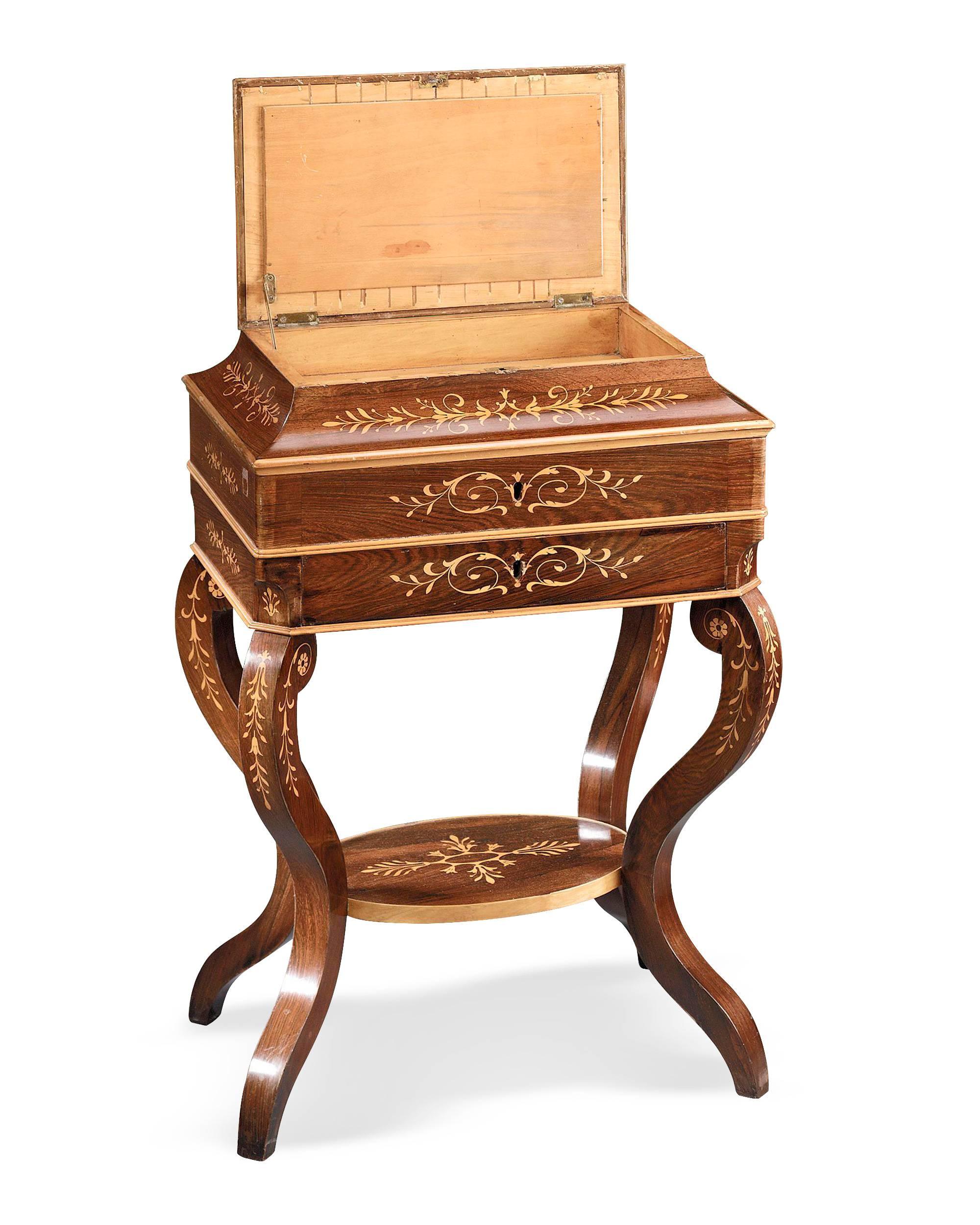This fine Charles X rosewood sewing stand rests upon beautifully curved legs and is adorned with satinwood marquetry. The Stand is equipped with plenty of storage including a fitted tray with several compartments that lift out, a drawer and a