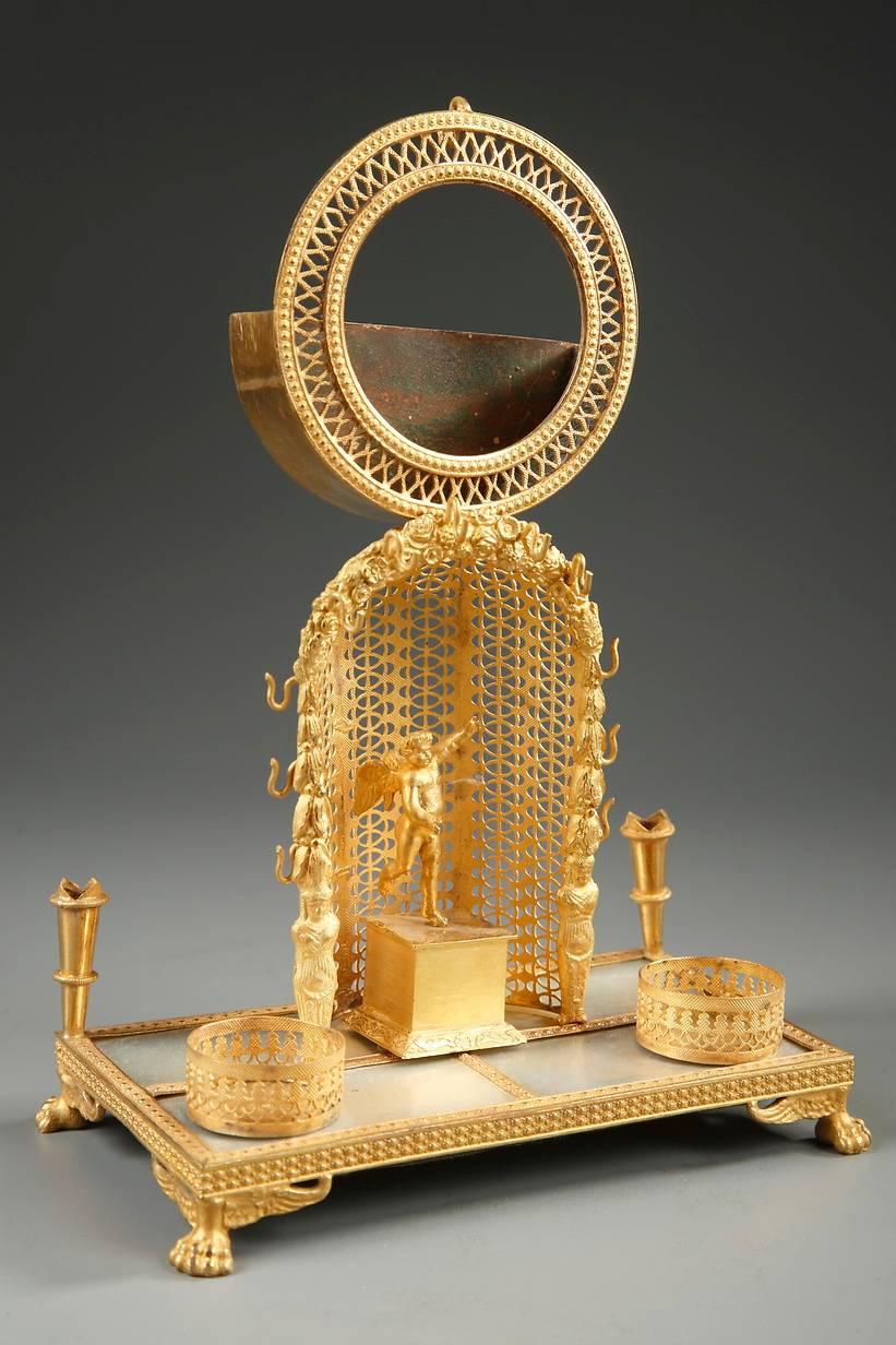 Mother of pearl and Ormolu watch holder and inkwell. The center of the piece is decorated with an angel who is standing on a pedestal that rests in a semi-circular niche. The niche is formed with openwork tracery, and its edges are adorned with