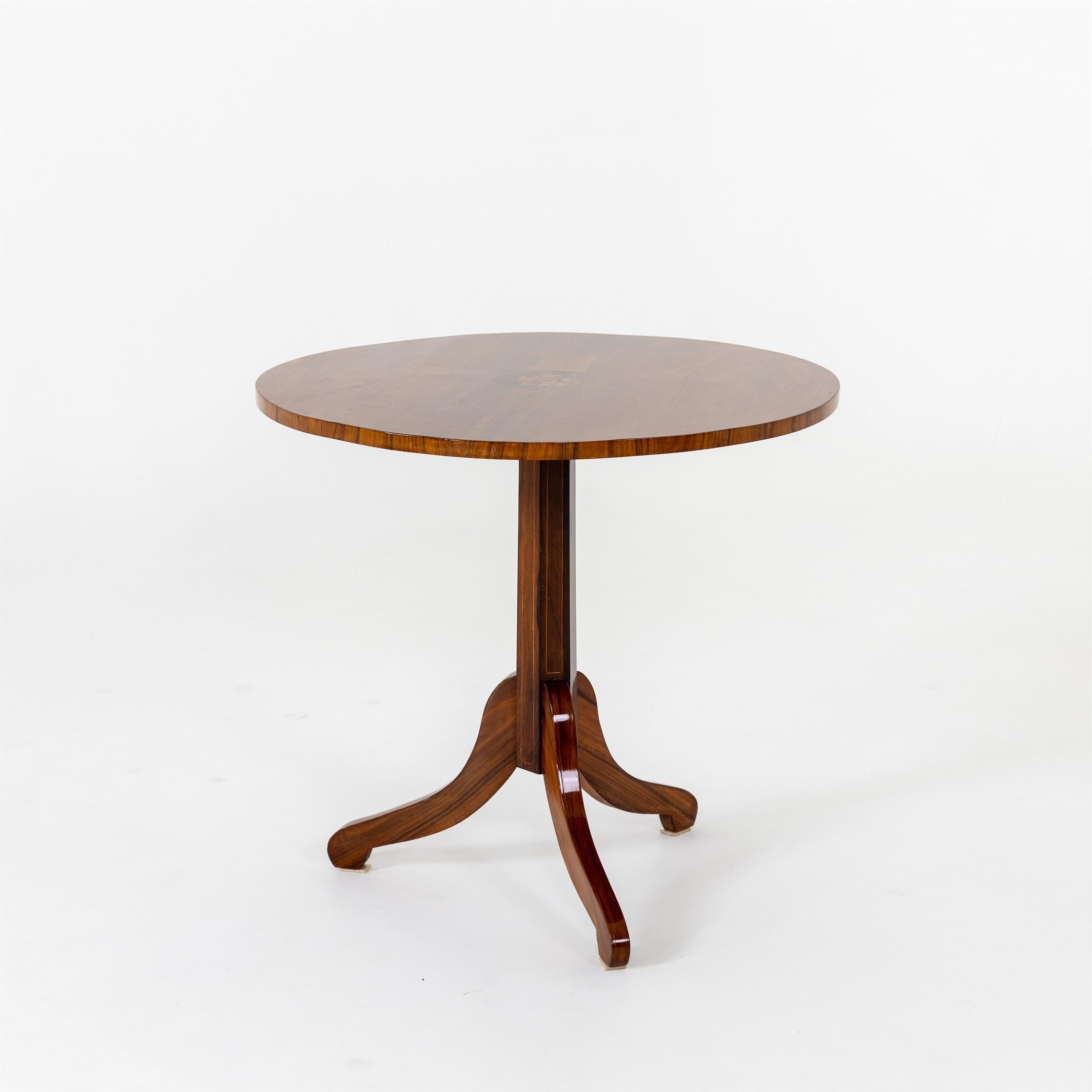 Charles X side table on a three-legged stand with octagonal column base and round tabletop. This, like the stem, is decorated with fine radial thread inlays as well as floral marquetry. The tabletop is hinged. The table was professionally