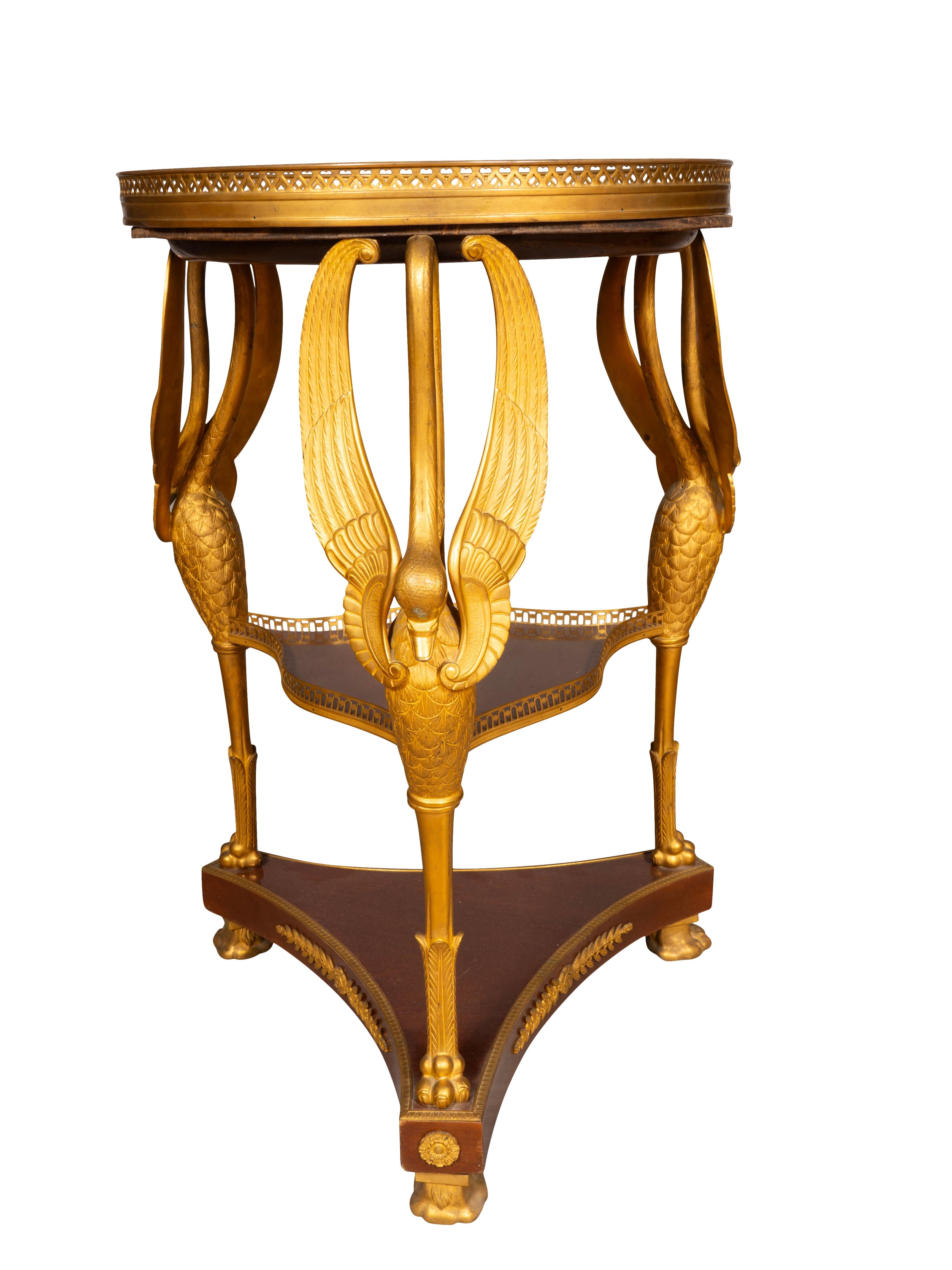 Piano circolare in marmo antico verde con galleria sollevata su supporti a forma di cigno in bronzo dorato uniti da due ripiani inferiori, piedi a zampa.