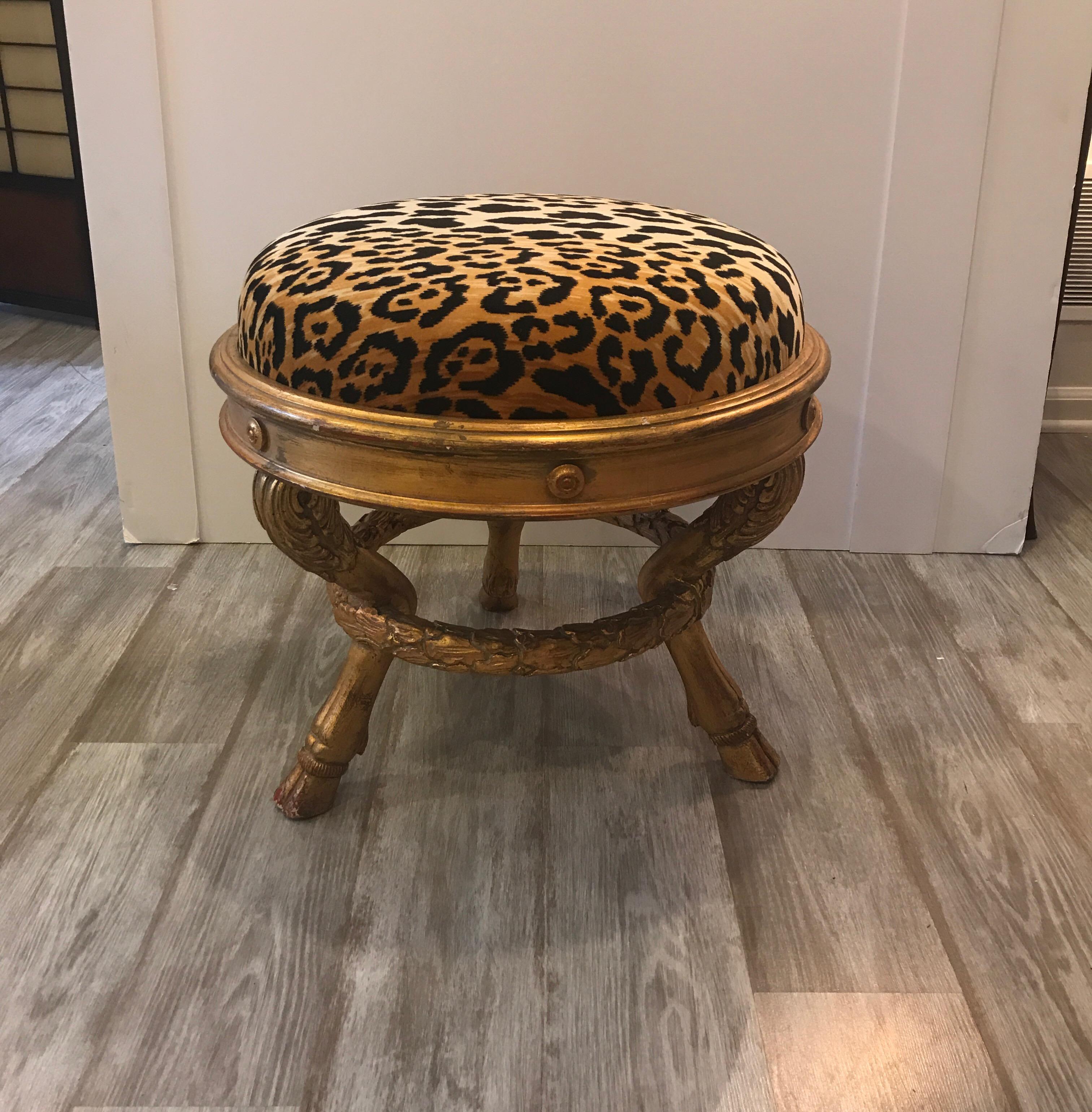 A chic round giltwood bench, in the Charles X style with new leopard print velvet upholstery. The three carved legs with hoof feet supported by a circular carve s stretcher support.