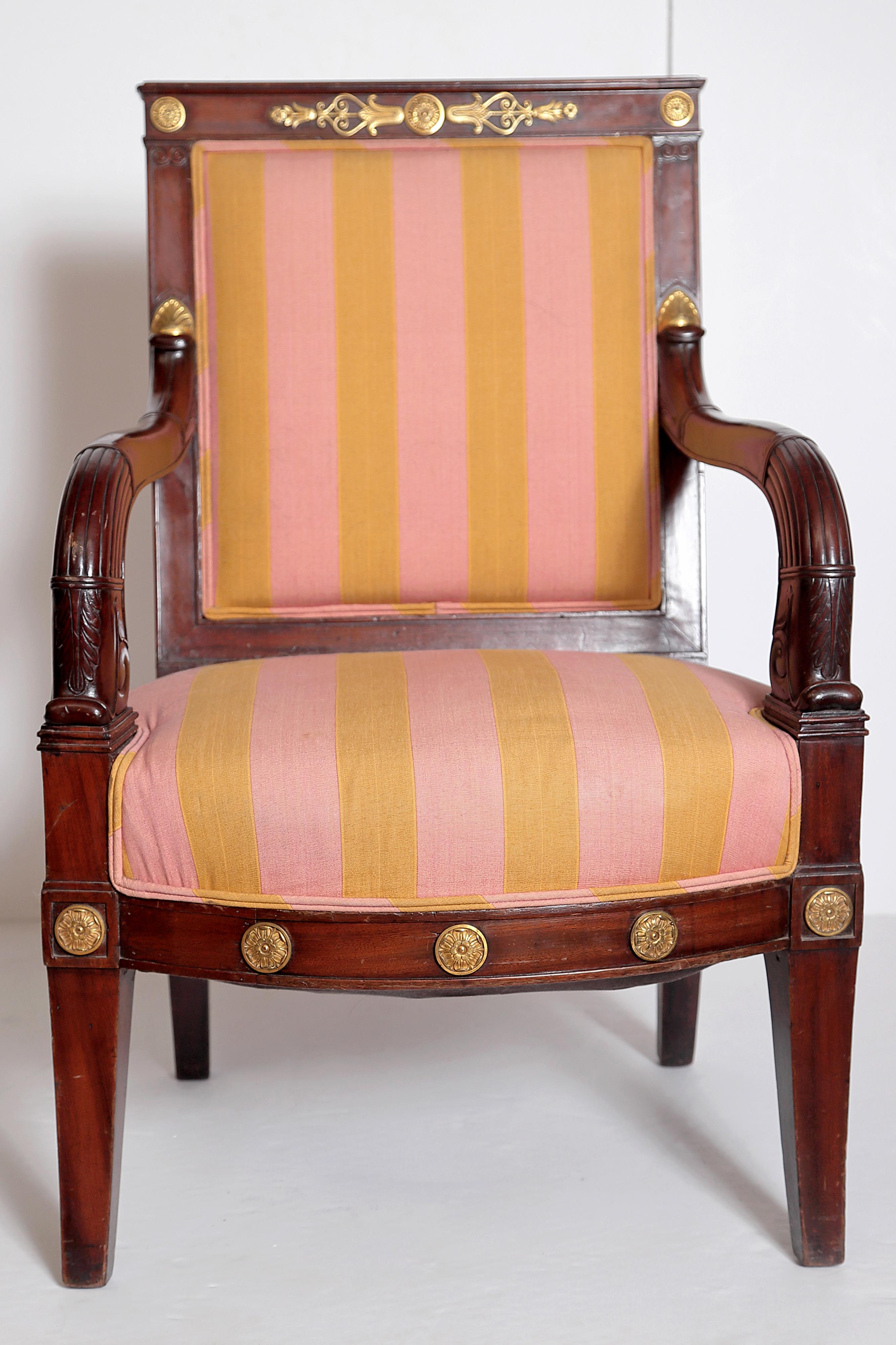 A Charles X walnut armchair / fauteuil with ribbed, curved arms, gilt bronze decoration / ornament on frame, straight legs, upholstered in a dusty rose and gold striped fabric

Measures: seat height 17