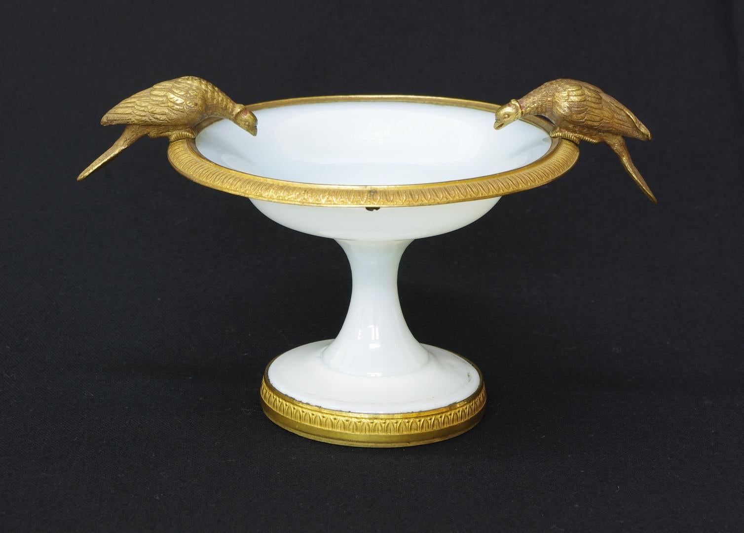Charles X white opaline coupe, the rim mounted with two drinking pheasants perched on a tooled band with leaf and berry decoration; the circular base with similar mounts.

Note the presence of the two additional screws on the back of the rim,