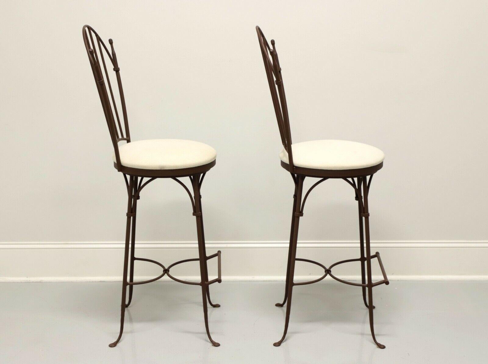 A pair of Contemporary style bar stools by Charleston Forge. Wrought iron with a Shaker arch back, cream colored fabric upholstered round seats that swivel, arced stretchers and bar foot rest. Made in Boone, North Carolina, USA, in the early 21st