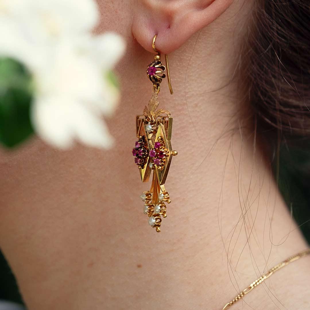 Orecchini pendenti originali d'epoca Charleston (anni '20) in oro 18 ct, con pietre rosse e mezze perle. Con ganci a cerniera.

Misure: 
Lunghezza 6,5 cm  x Larghezza 1,7 cm