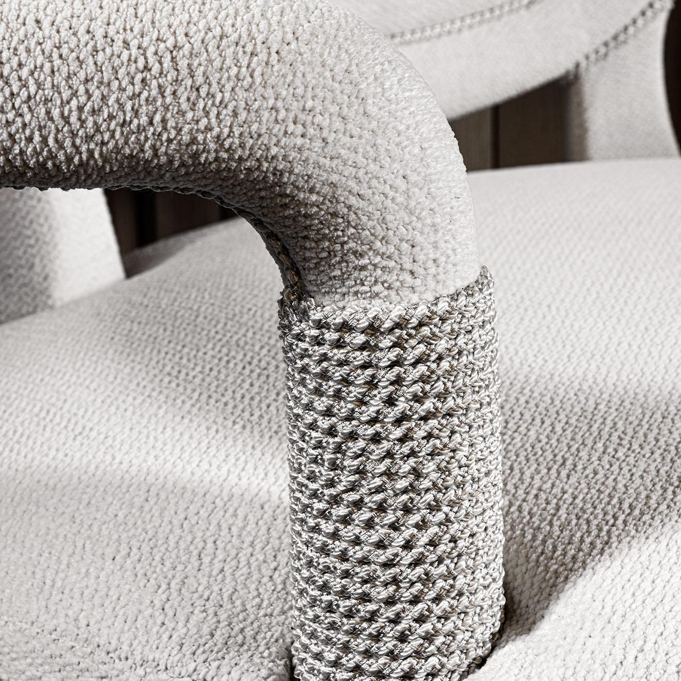 Ein mit weißem Chenille bezogener Stuhl, der mit dekorativen, kordelumwickelten Details verziert ist und Eleganz und Raffinesse ausstrahlt.