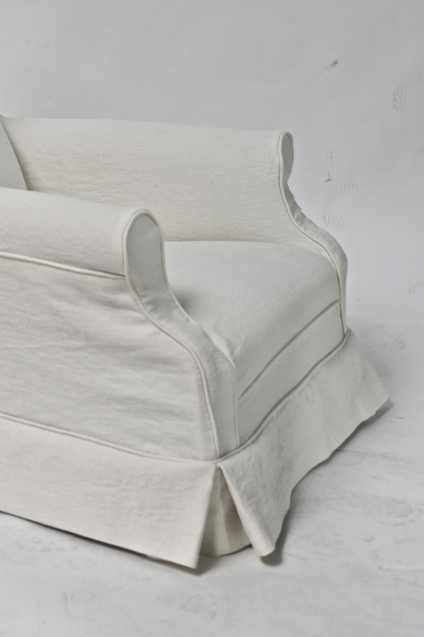 Le fauteuil club Charlotte d'am designs est une version raffinée et contemporaine de la silhouette club classique. Fabriqué à la main en Belgique avec un cadre en bois massif, il présente de larges accoudoirs, une assise profonde et un profil bas et